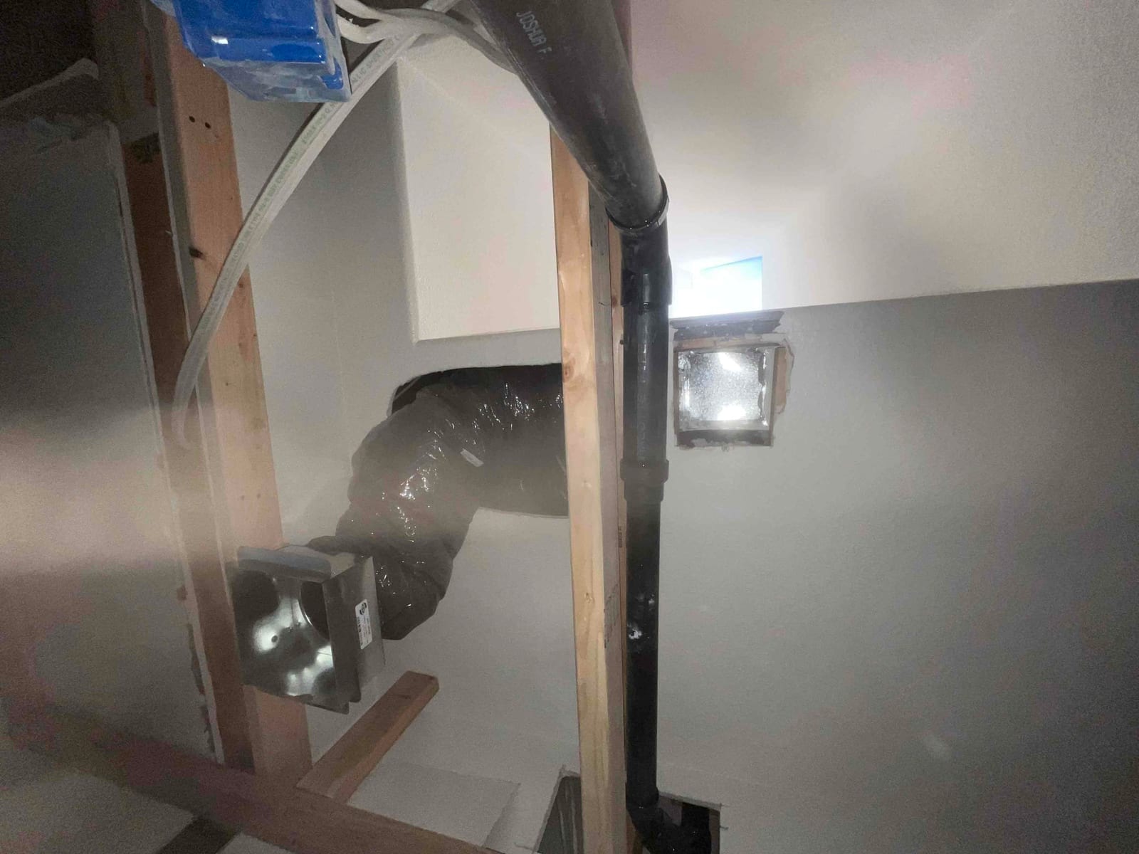 Flexible insulated supply duct rerouted across ceiling framing, with new return filter frame opening visible in the drywall.