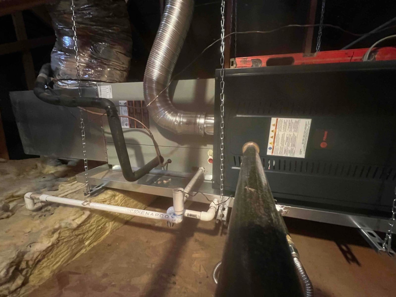 Horizontal attic air handler and furnace hung with chains, insulated duct connections, condensate drain piping, and flexible gas vent installed.