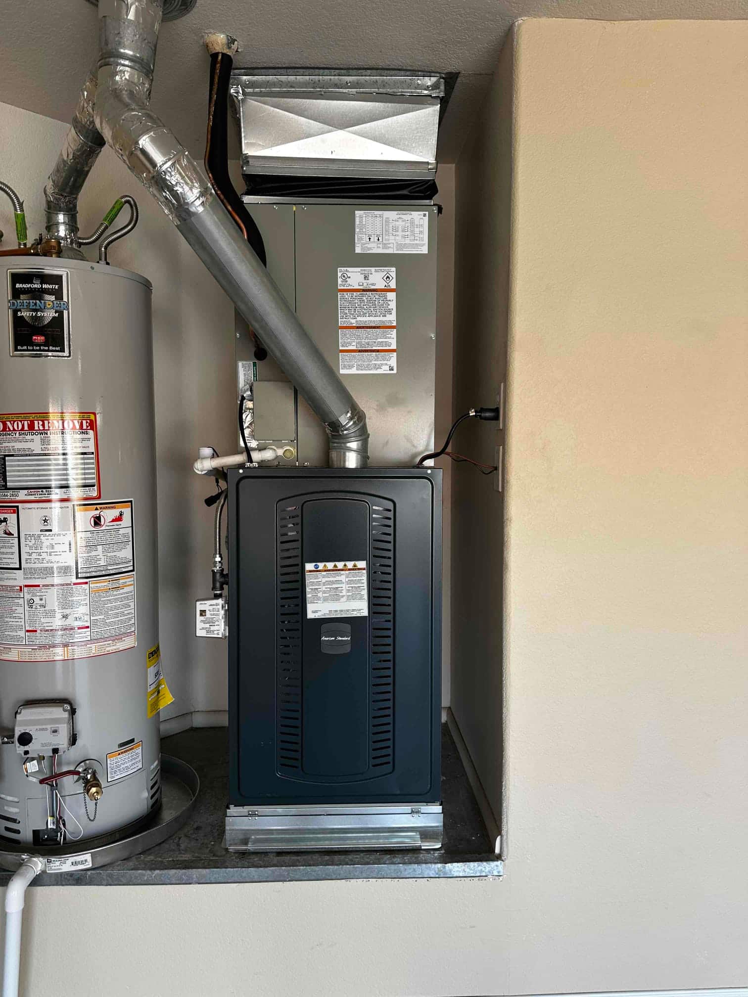 New gas furnace and coil installed next to a water heater, with venting, condensate drain, and supply plenum connected.