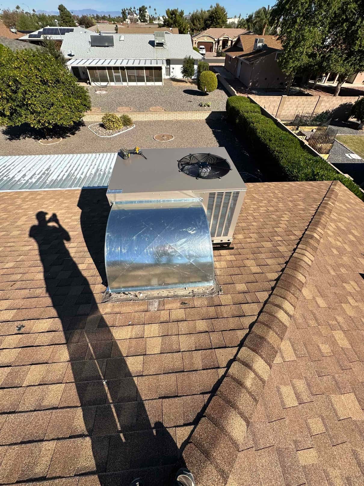 New rooftop package unit installed on curb with sealed supply plenum and roof flashing visible across shingle surface.