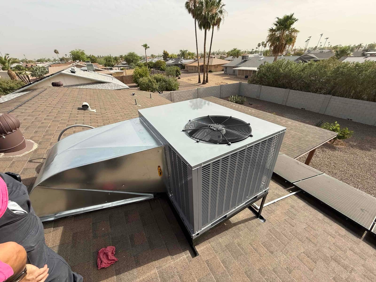 New rooftop package unit set on a stand with sheet metal transition curb, electrical whip, and roof walkway visible.