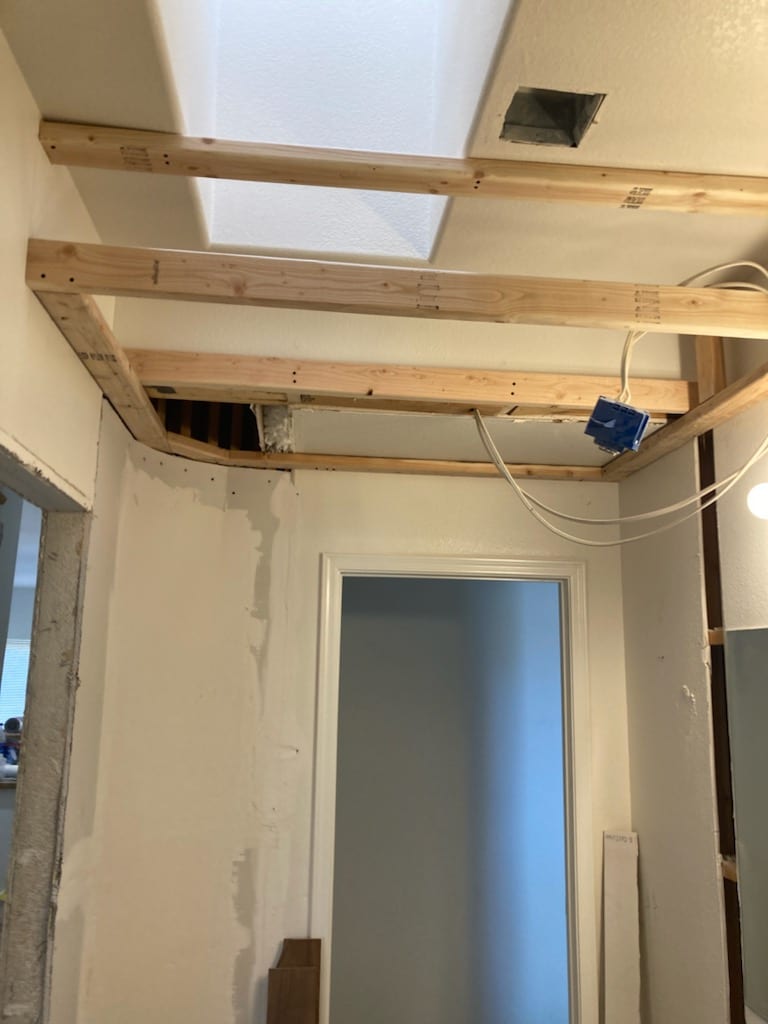 Open ceiling framing shows relocated supply duct path and new electrical box, with return opening near hallway.