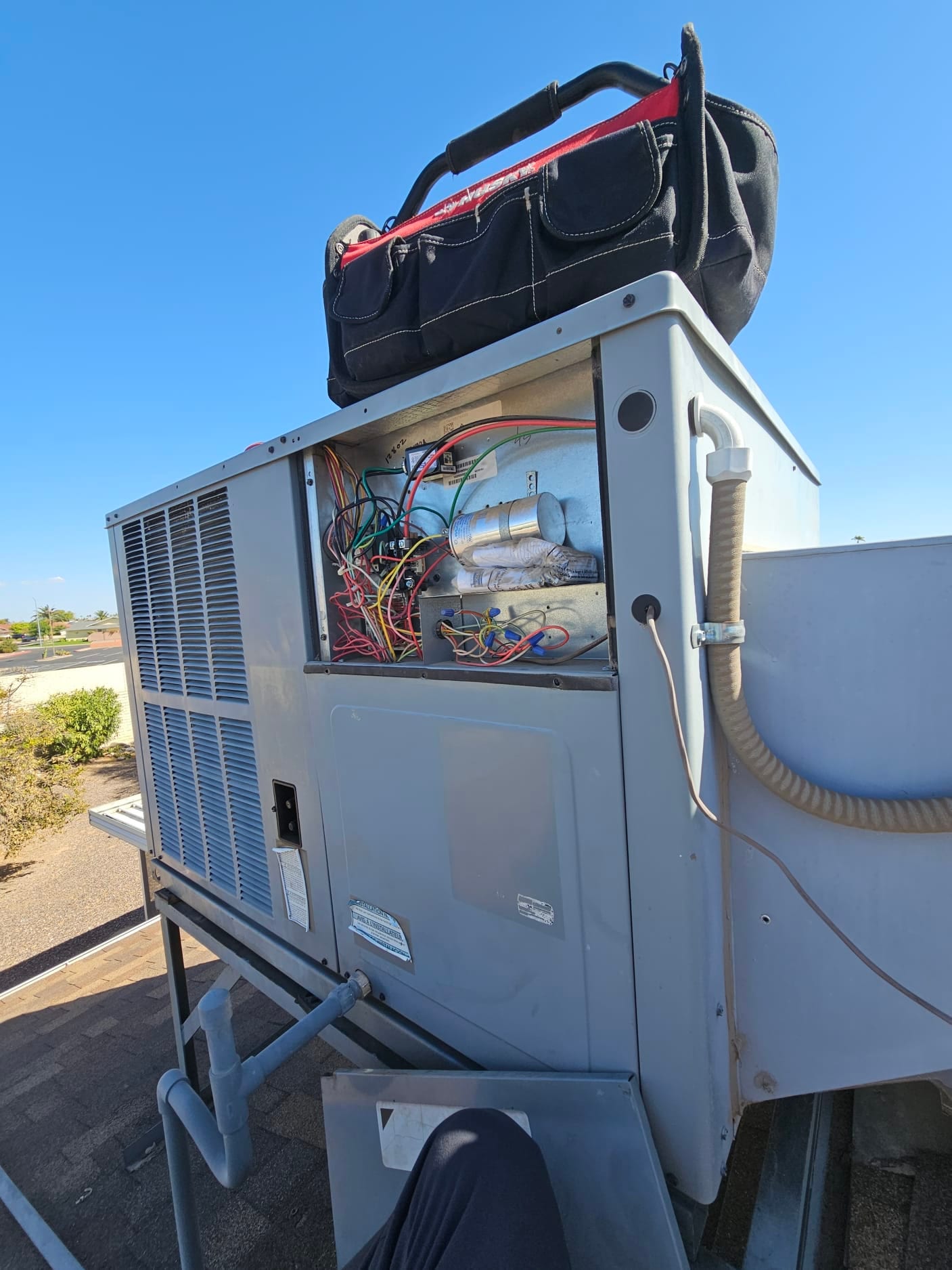 Open rooftop package unit electrical compartment with dual run capacitor, contactor, and wiring exposed.