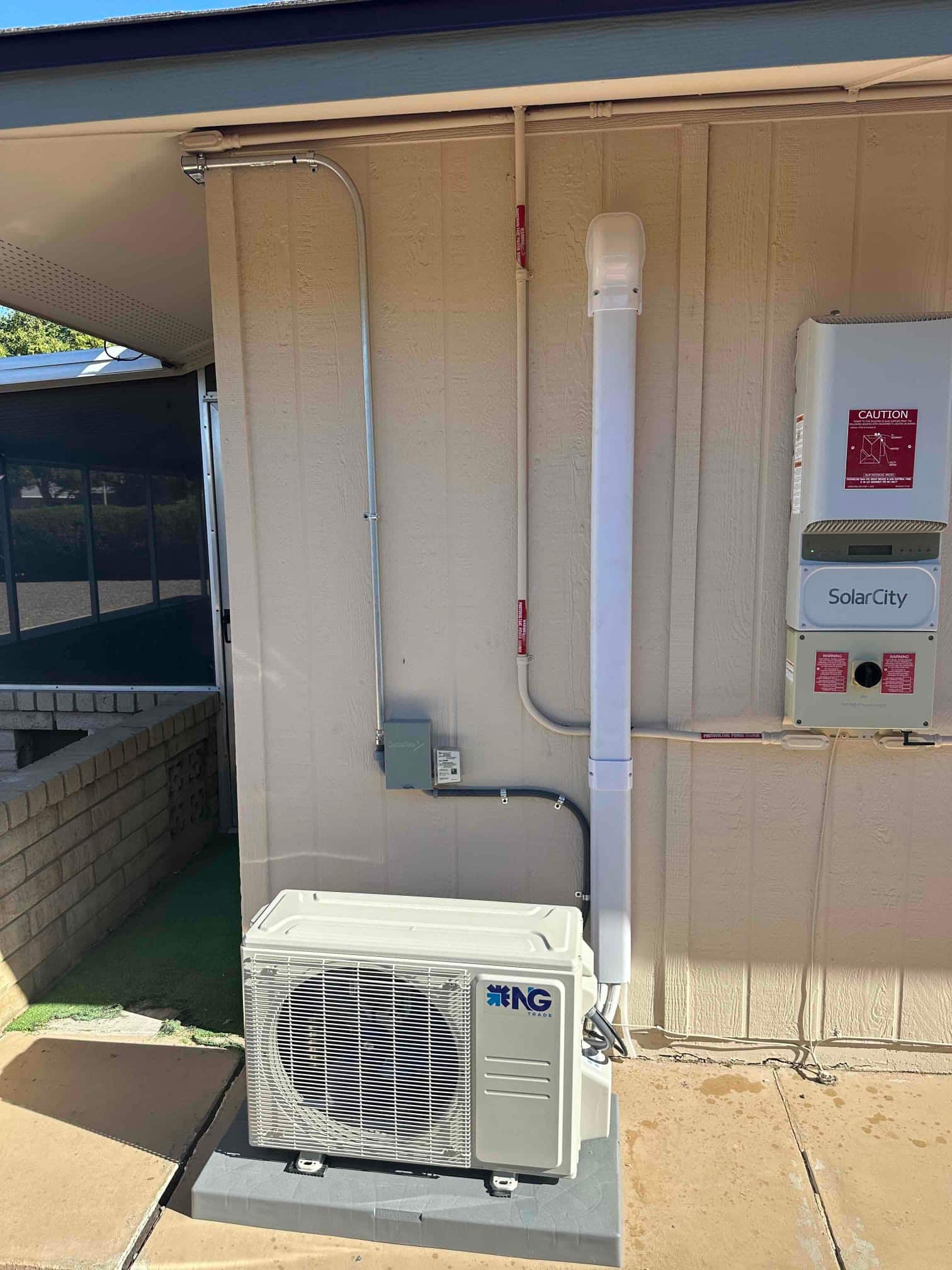 Outdoor heat pump condenser set on a level pad with line hide, electrical whip, and weatherproof disconnect installed.