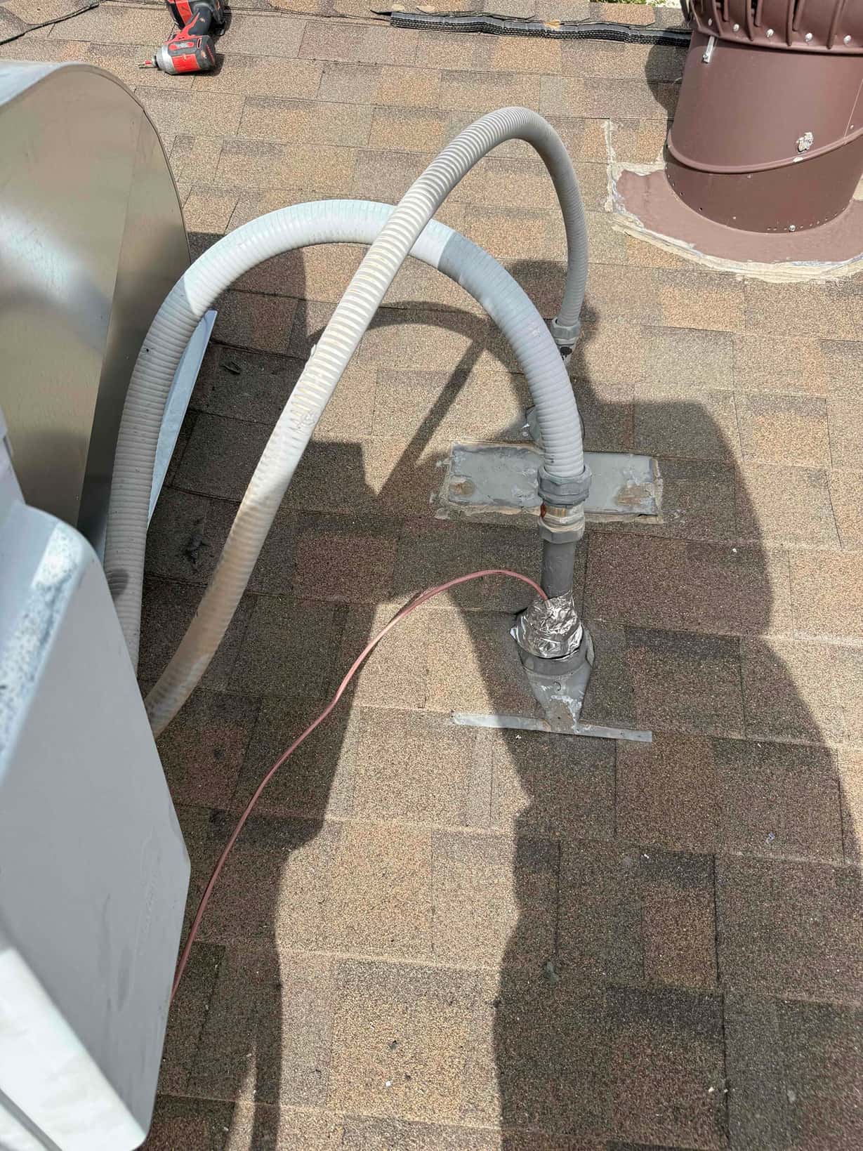 Rooftop conduit and flexible line set connections sealed at roof penetrations beside the newly installed package unit.