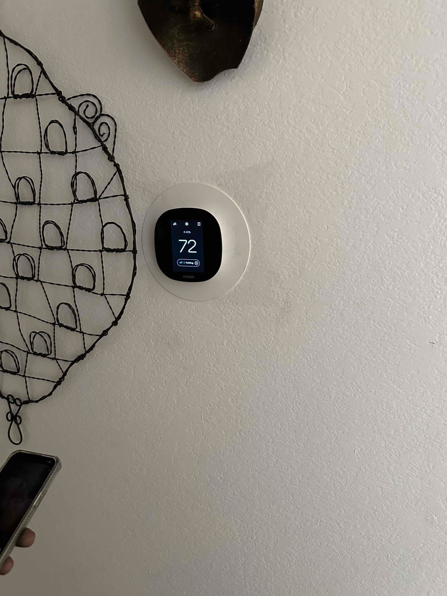 Smart thermostat mounted on interior wall displaying 72 degrees, confirming thermostat installation and system control interface.
