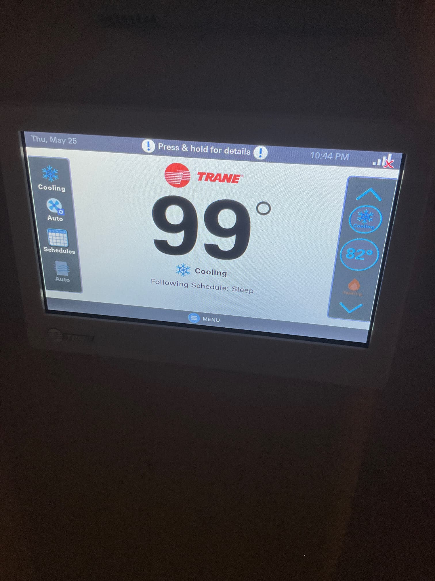 Wall-mounted thermostat display shows indoor temperature at 99 degrees while system mode is set to cooling.