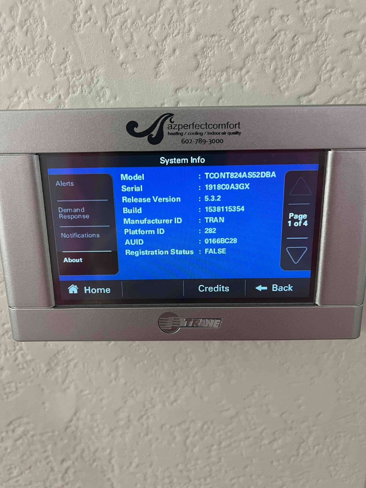 Wall-mounted touchscreen thermostat powered on, displaying system information after installation at the indoor location.