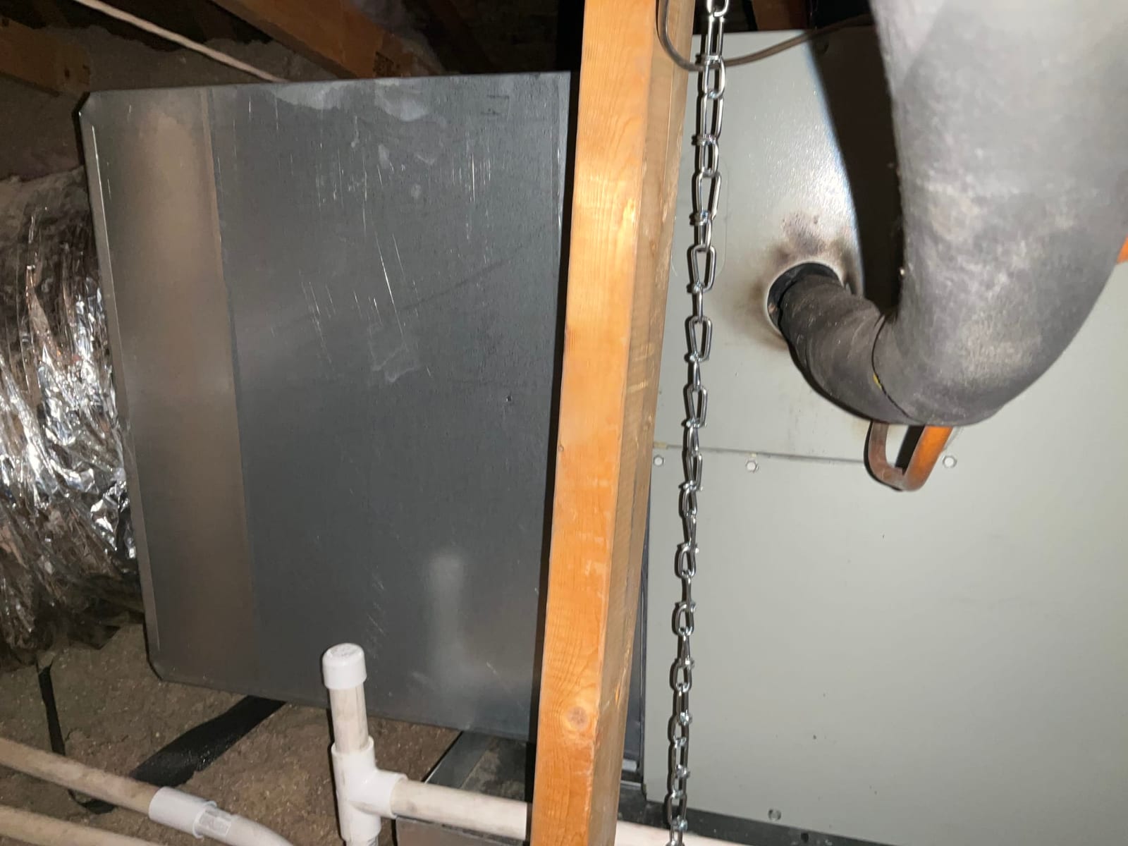 Air handler installed in attic with insulated refrigerant lines, sheet metal transition, flexible duct connection, and PVC condensate drain piping.