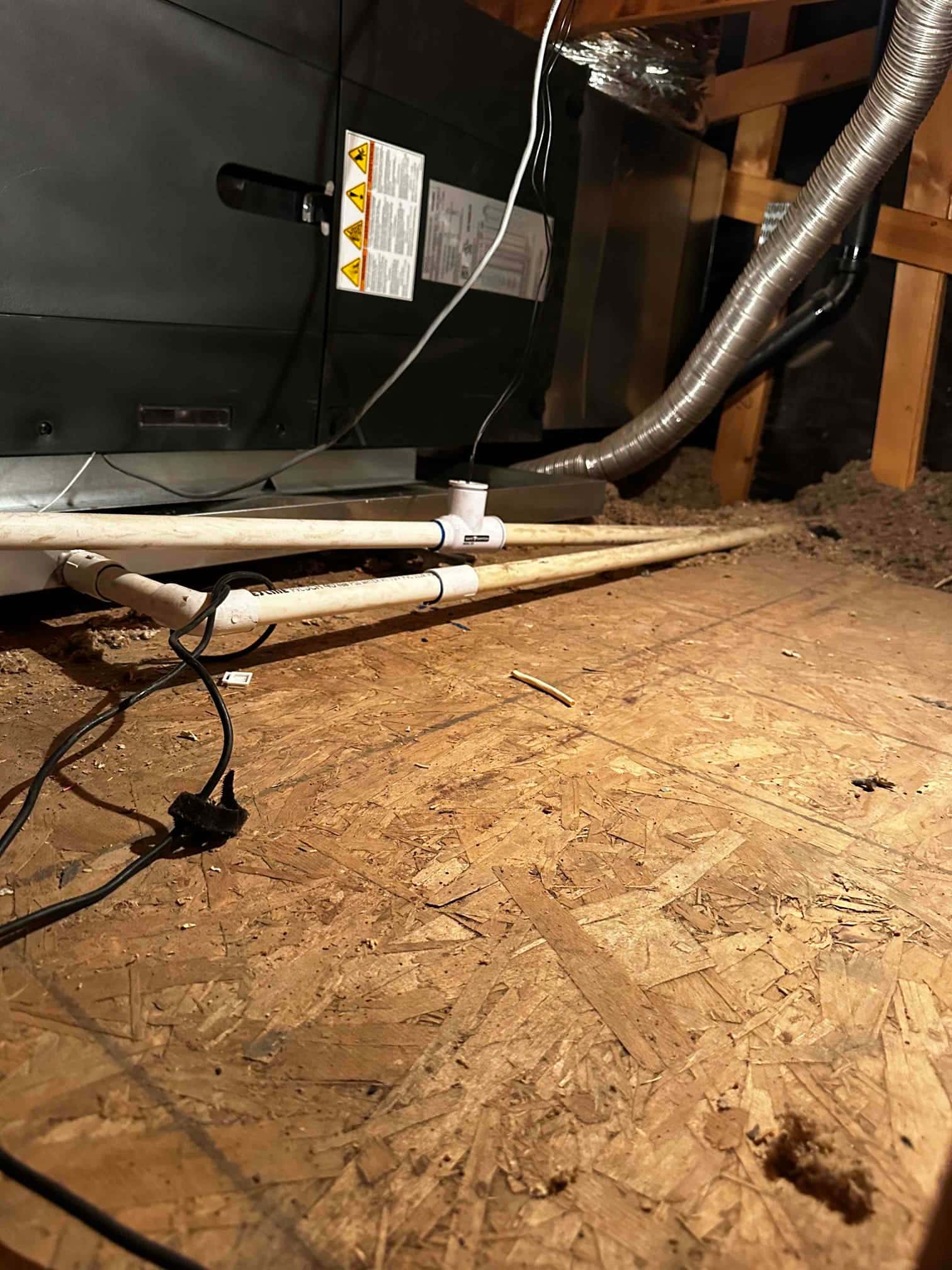 Air handler installed on a drain pan with new PVC condensate lines and flexible duct connection in the attic.