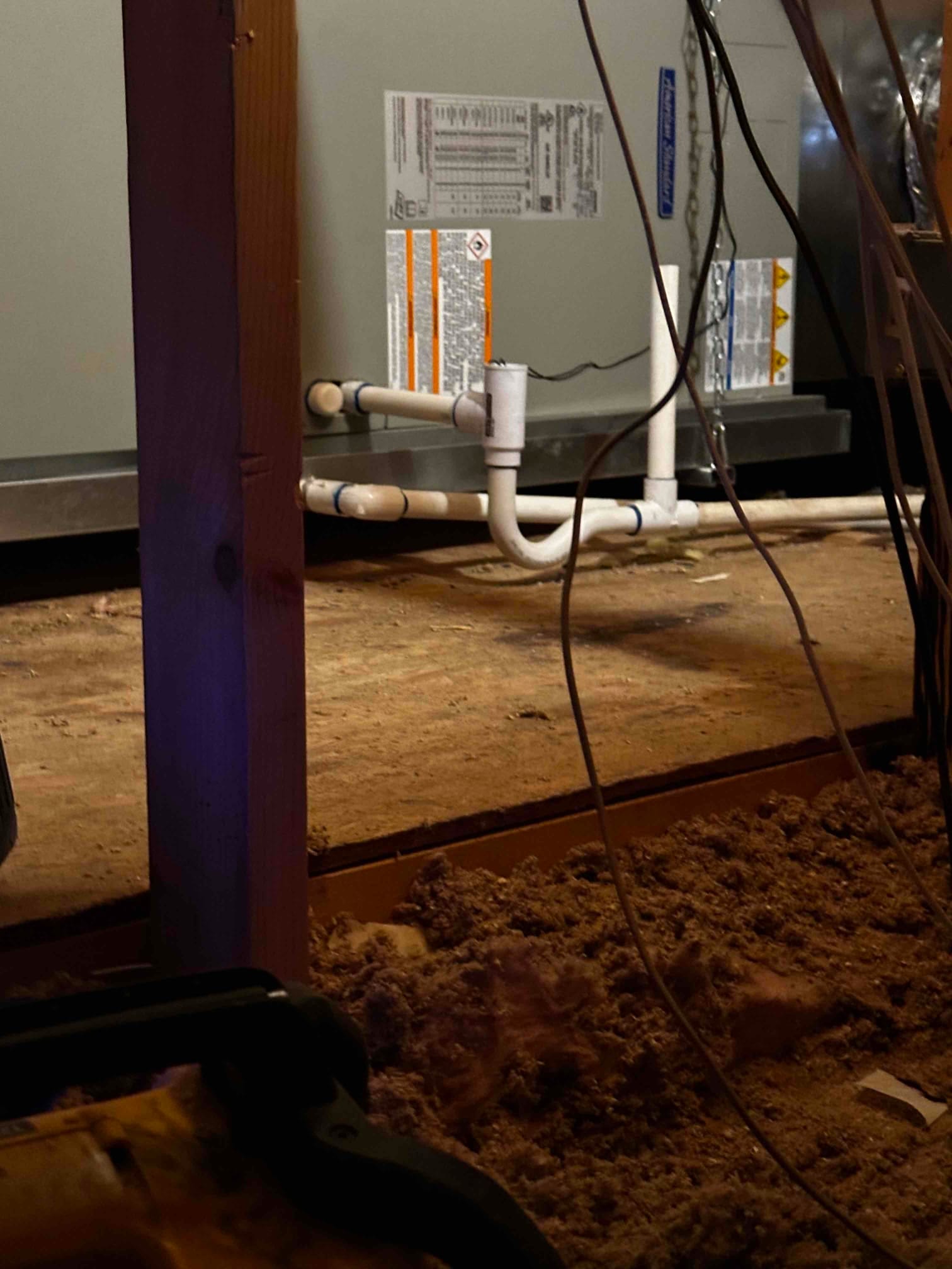 Air handler installed on a drain pan with newly plumbed PVC condensate drain and cleanout in an attic space.