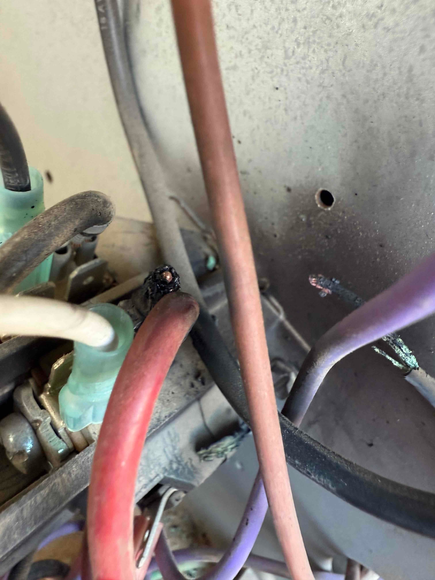 Burnt and melted wire insulation inside the condenser control area, with adjacent wiring and terminals showing heat damage and corrosion.