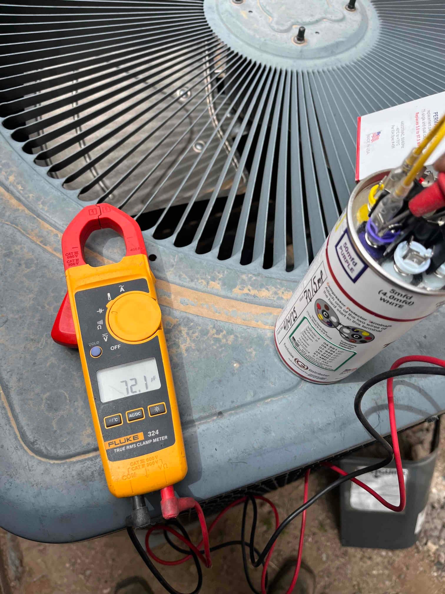 Clamp meter displays 72.1 µF while measuring the run capacitor connected to the outdoor condenser unit.