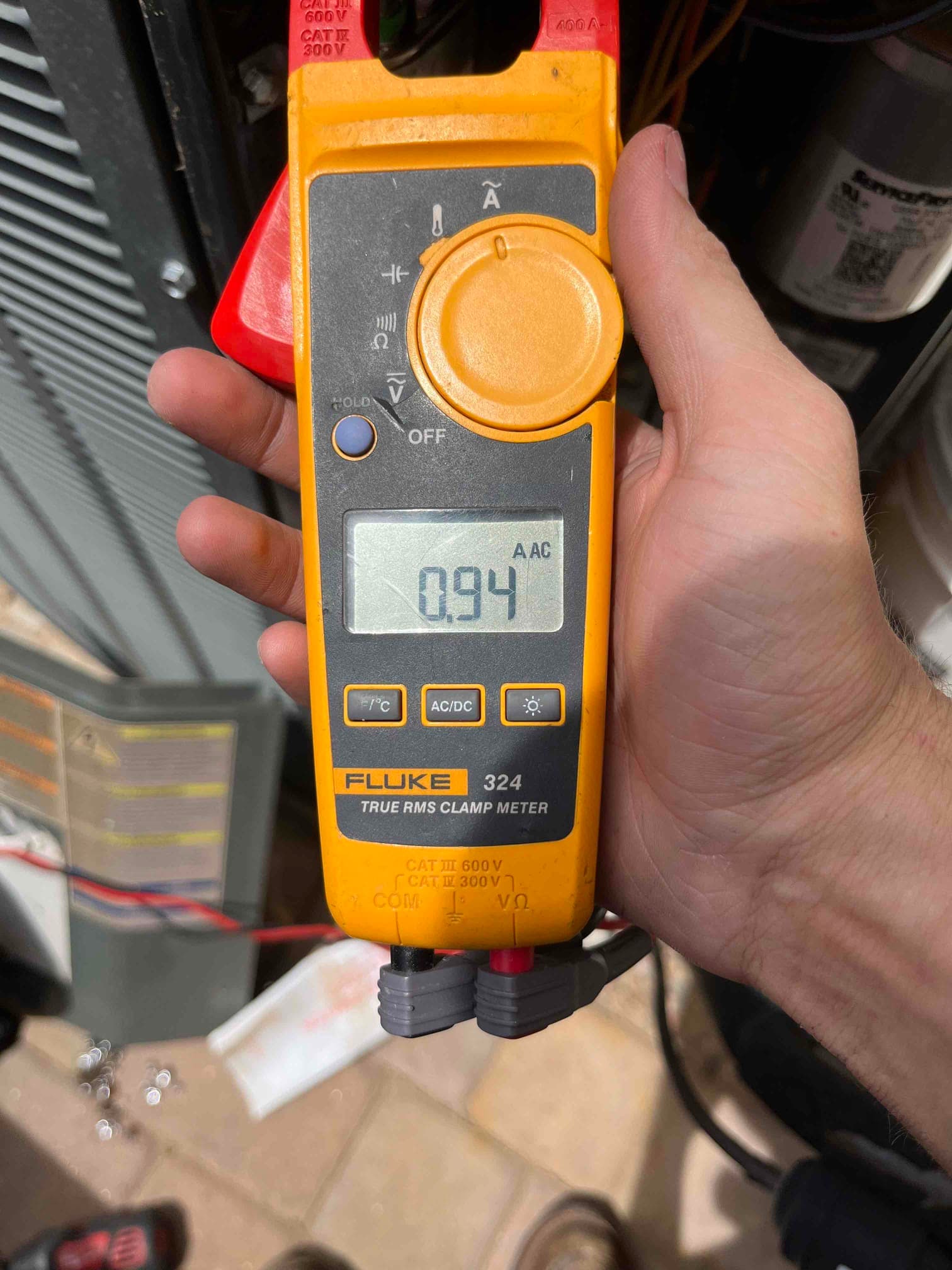 Clamp meter shows 0.94 A AC on the conductor while testing the air conditioning system during repair.