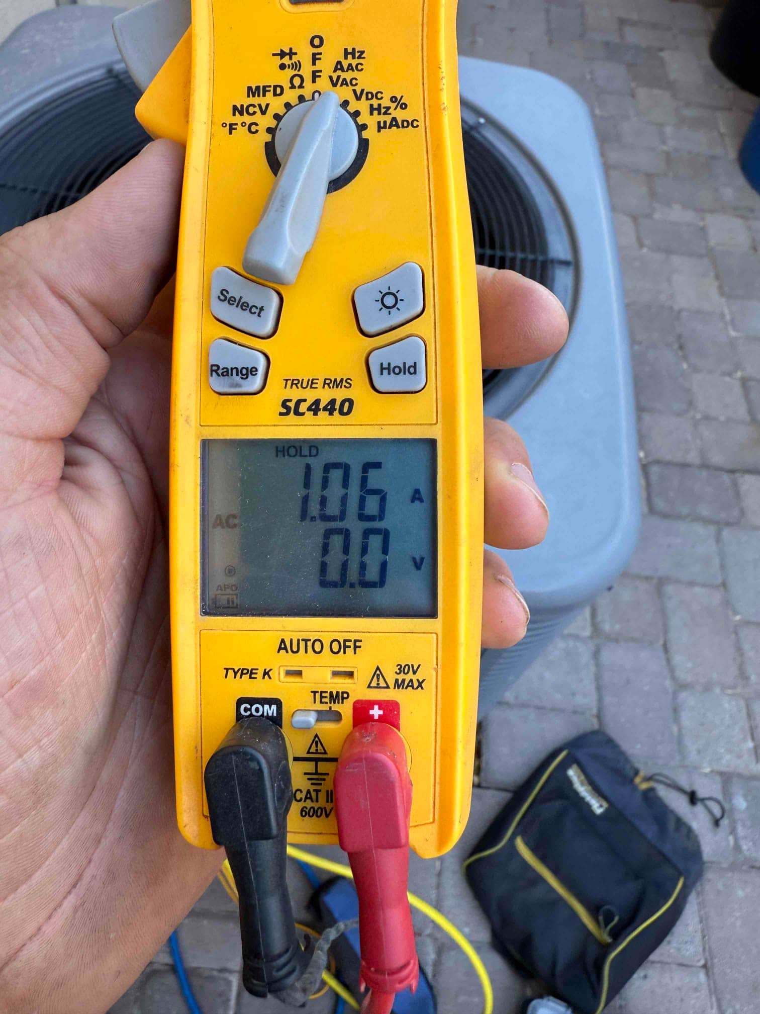Clamp meter shows 1.06 A on a conductor at the outdoor condenser while the unit operates.