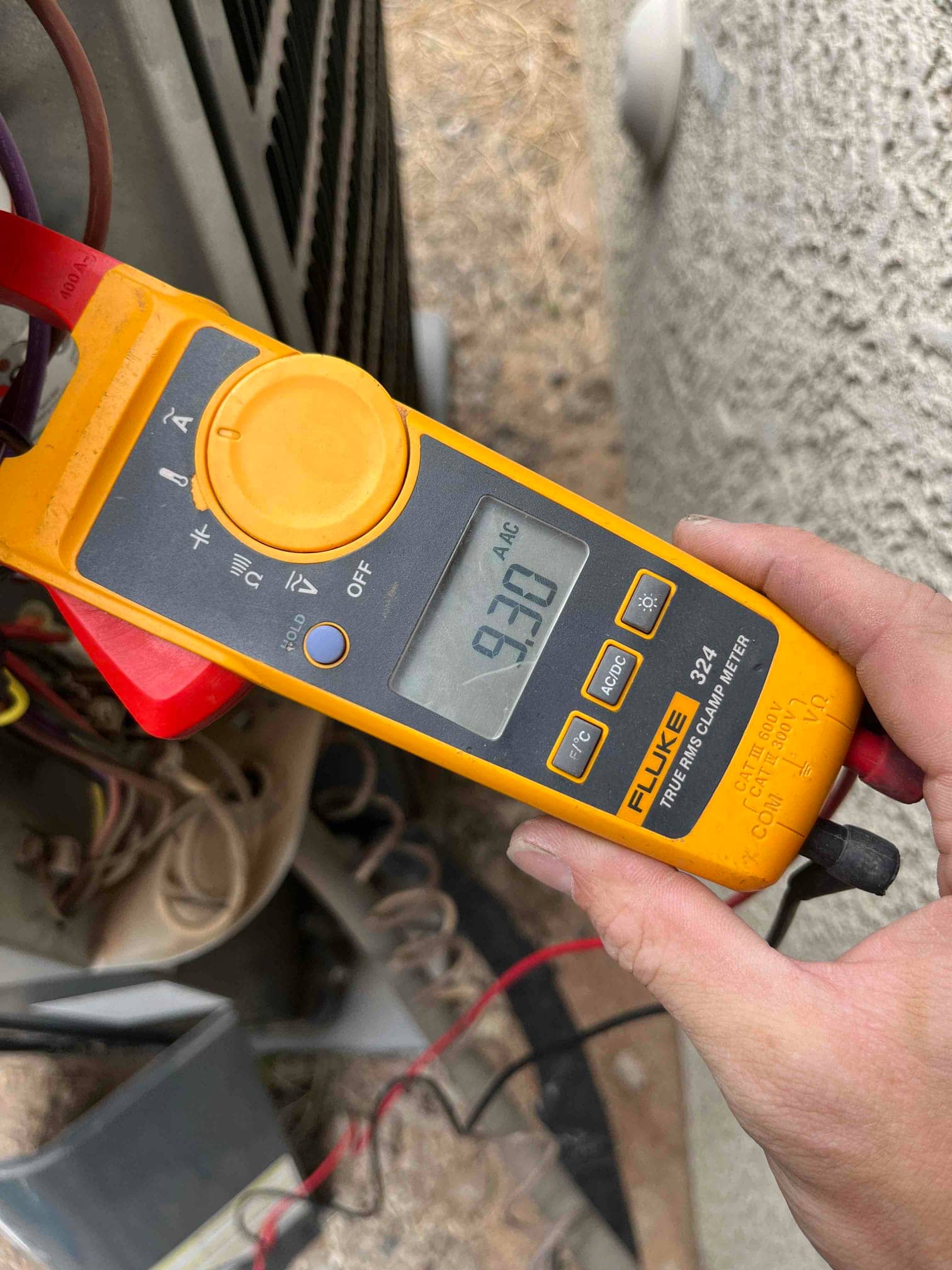 Clamp meter shows 9.30 A AC current on a clamped conductor at the outdoor condenser unit.
