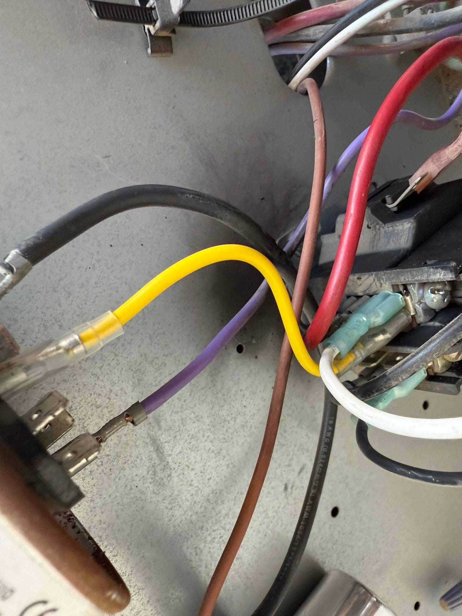 Close-up of condenser compartment wiring, showing new yellow jumper with crimp connectors and multiple insulated spade terminals.