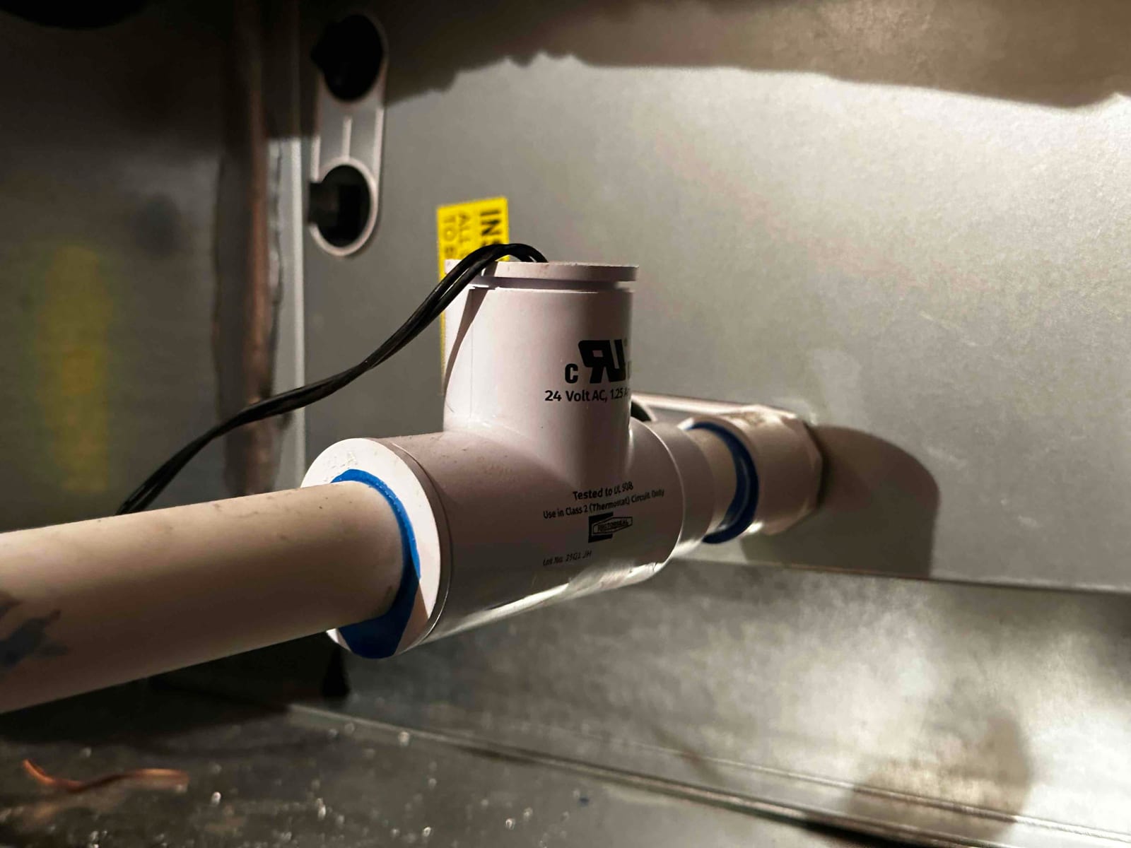 Condensate drain assembly with an inline float safety switch installed on PVC piping at the air handler.