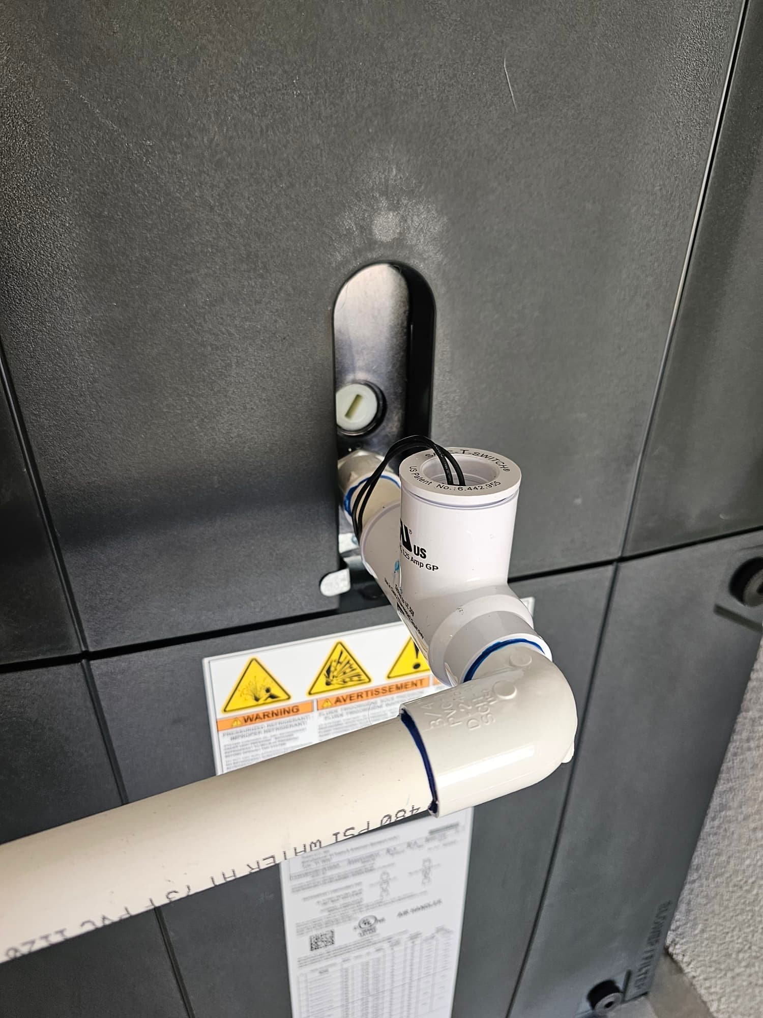 Condensate drain with float safety switch installed on the air handler, with PVC piping routed and glued at elbows.