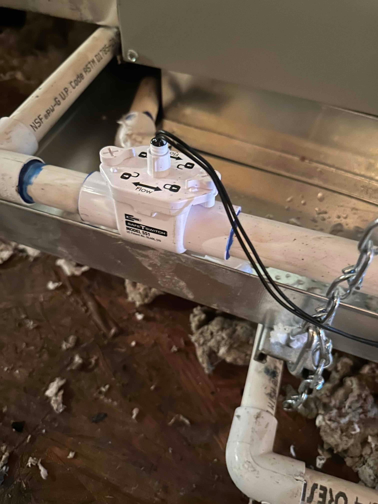 Condensate drain with inline float safety switch installed on PVC piping beneath the air handler, with wiring routed for overflow protection.