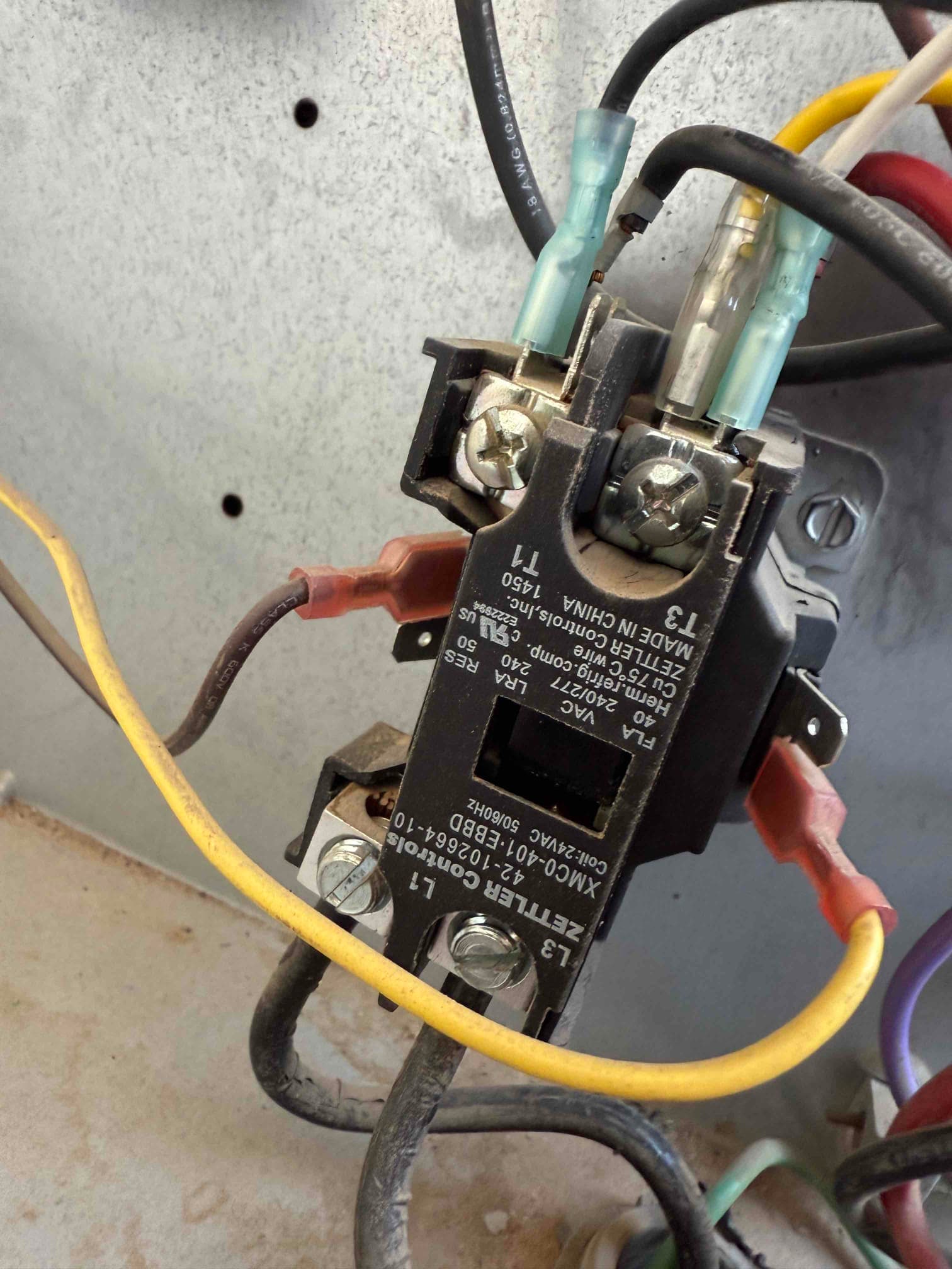 Contactor inside outdoor unit cabinet showing connected line and load wires with insulated spade terminals on the coil.