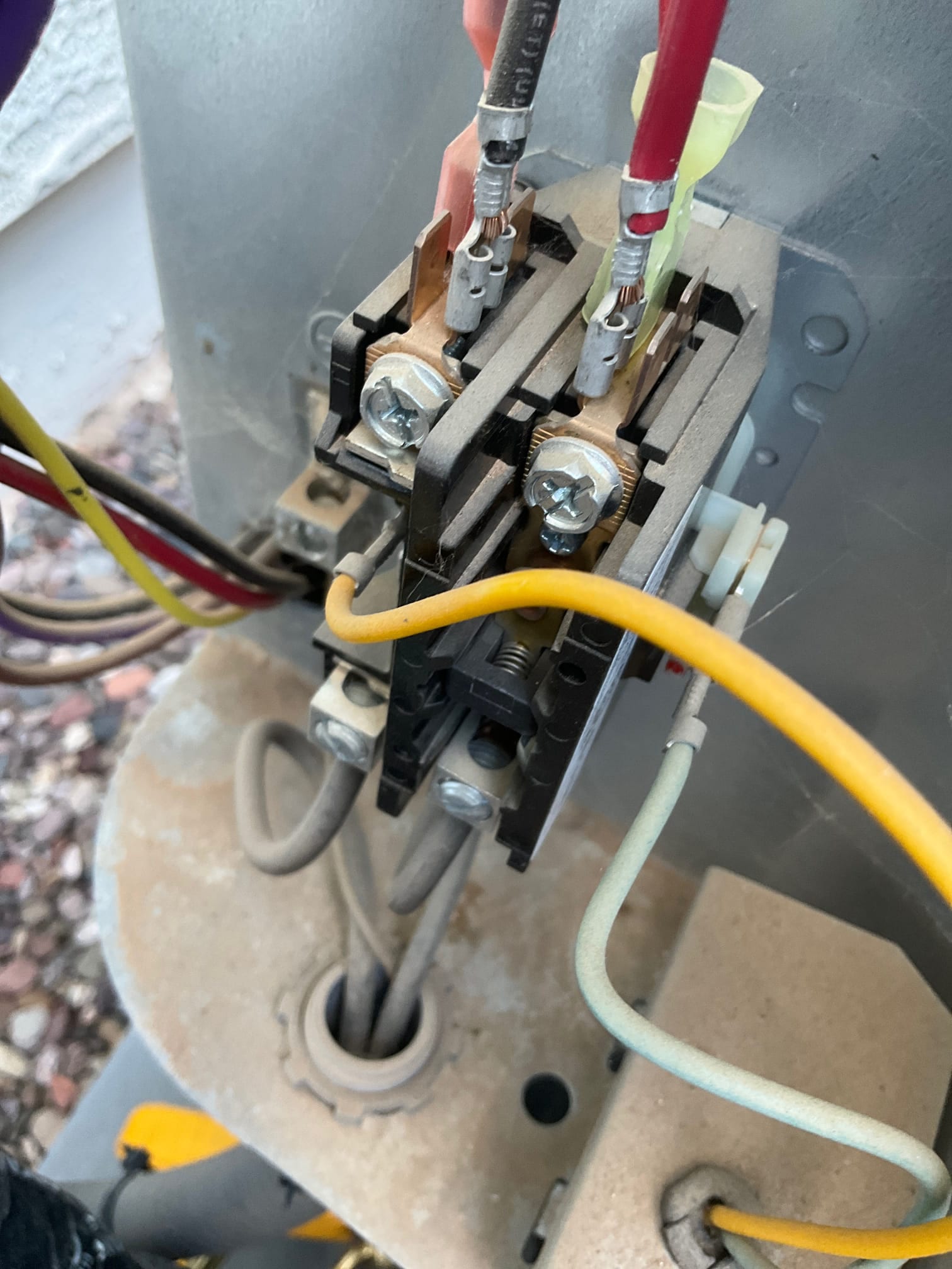Contactor with line and load wires connected; copper terminals and screws visible inside outdoor unit.
