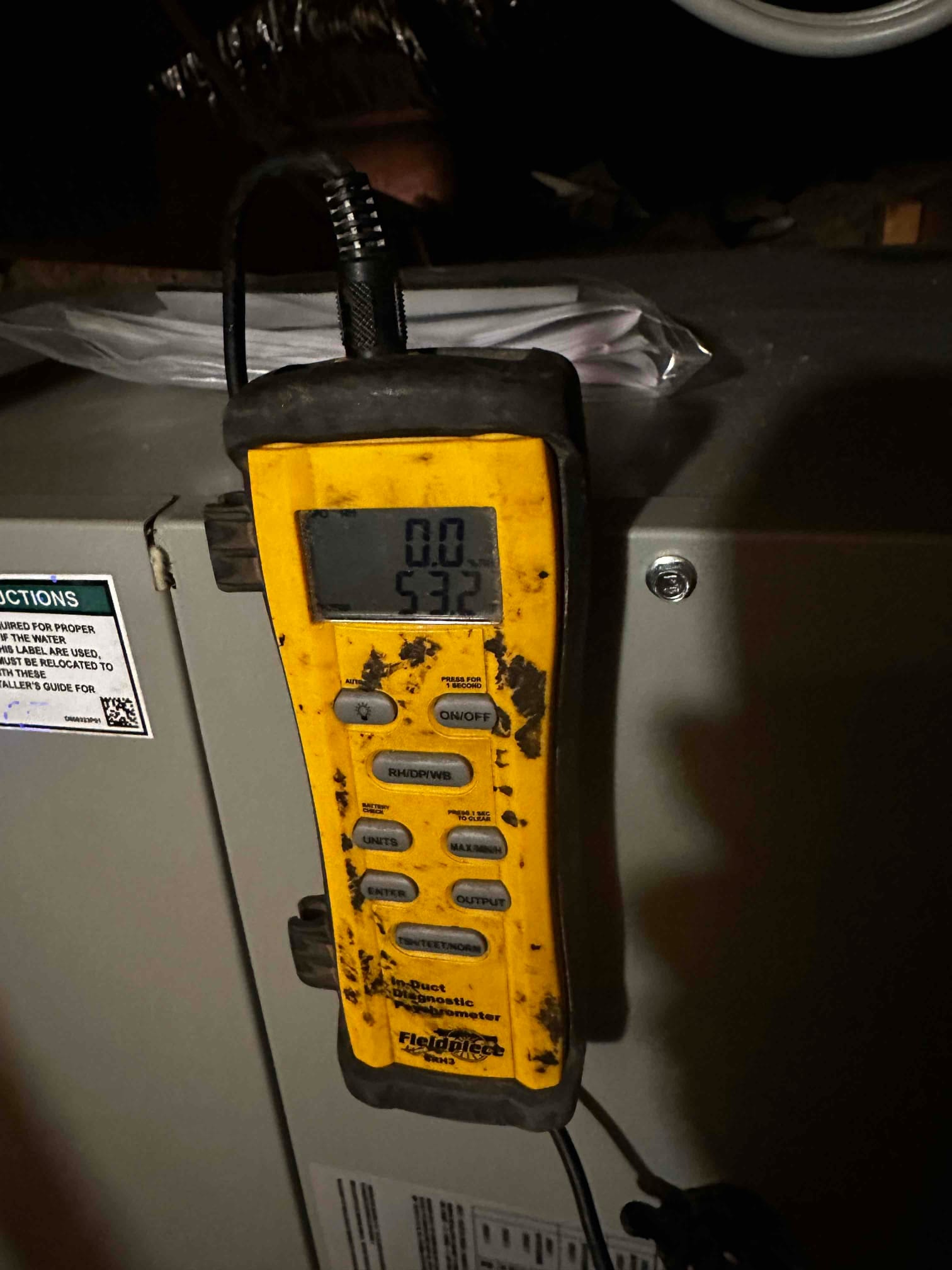 Digital in-duct thermometer mounted on the air handler shows a temperature reading of 53°F during airflow testing.