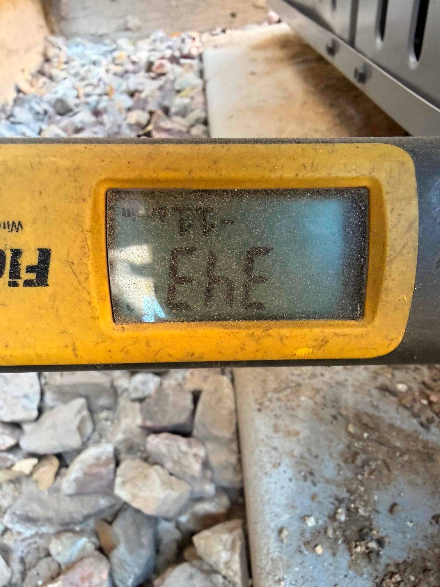 Digital level placed on the outdoor unit base to verify the condenser sits level on the installed pad.