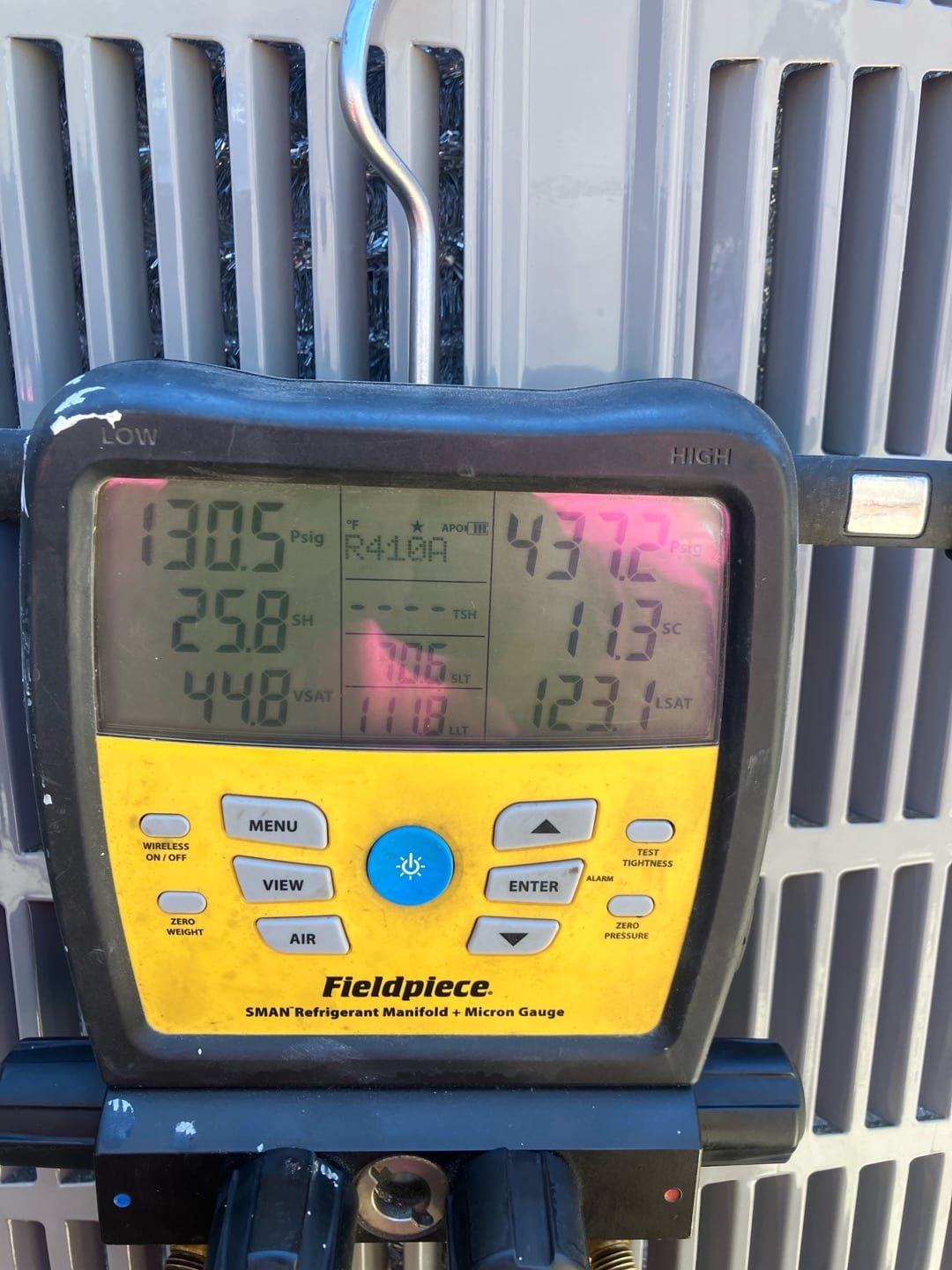 Digital manifold connected to the condenser shows operating pressures during system commissioning with both low and high sides displayed.