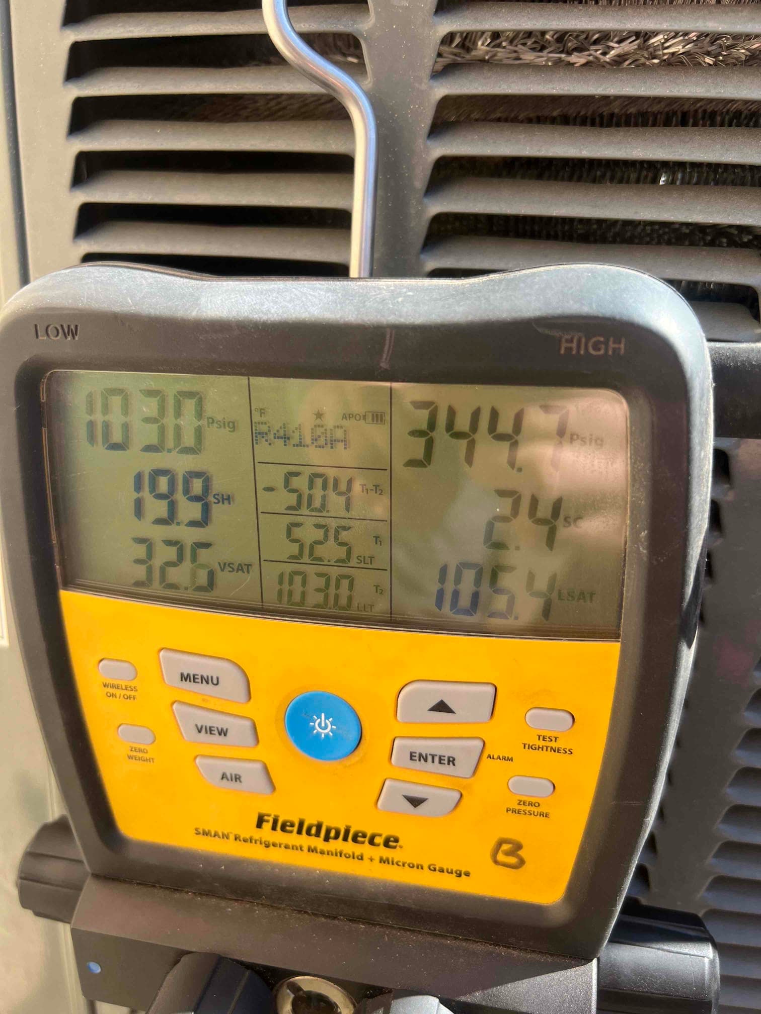 Digital manifold gauge connected to an outdoor condenser shows high-side pressure at 344.7 psi and low-side at 199 psi.