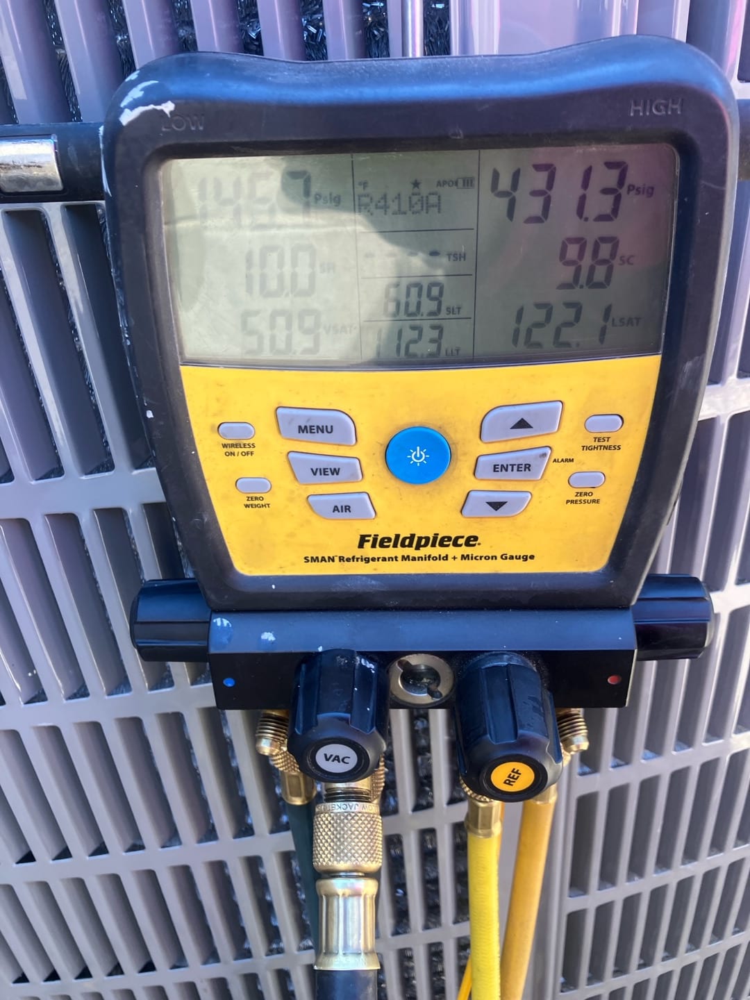 Digital manifold on the outdoor unit shows operating pressures with R-410A selected during system commissioning.