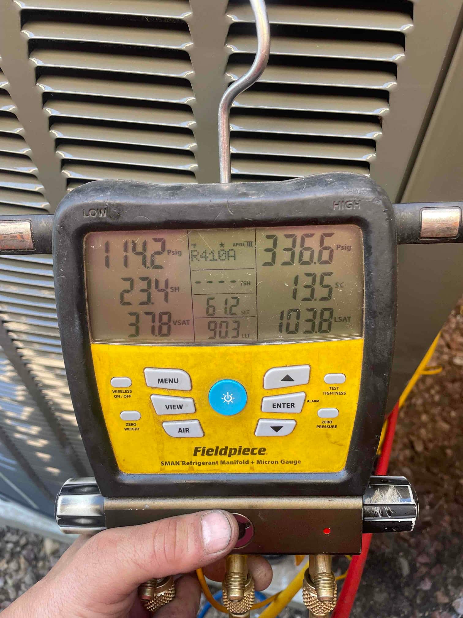 Digital manifold shows system operating with low side 114 PSIG and high side 336 PSIG on R‑410A during commissioning.