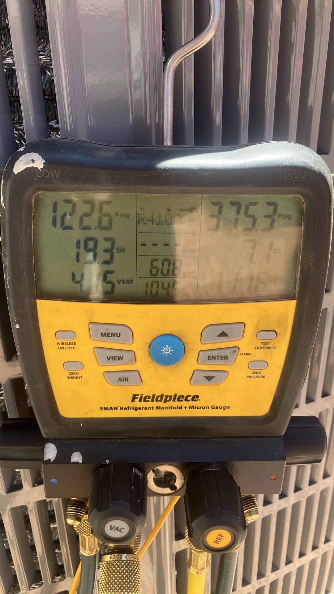 Digital manifold shows system operating with low side at 122.6 PSI and high side at 375.3 PSI during commissioning.