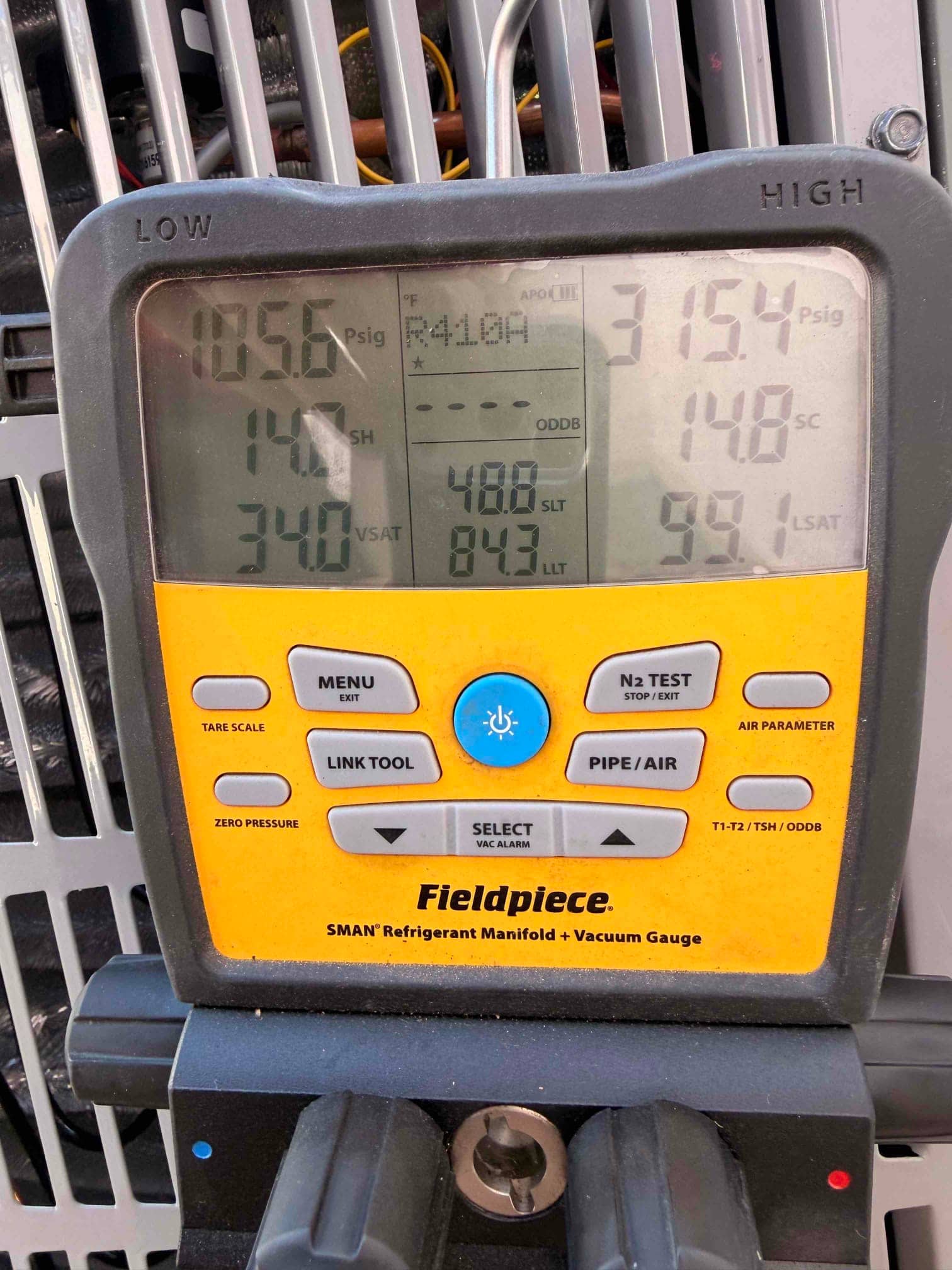 Digital manifold shows system operating pressures with low side at 106 psig and high side at 315 psig on the outdoor unit.