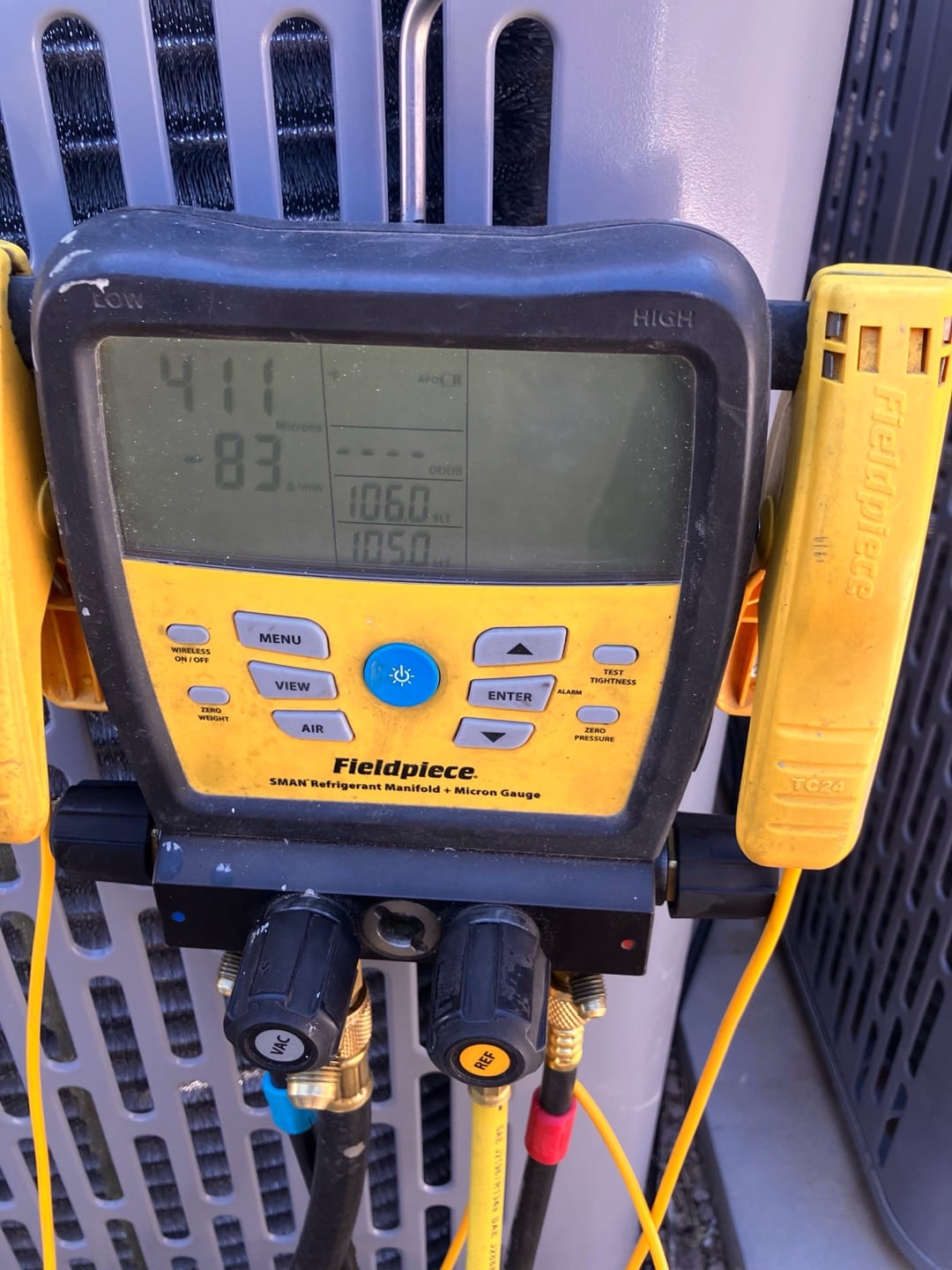 Digital micron gauge connected at the condenser shows 411 microns, confirming a deep vacuum during system evacuation.