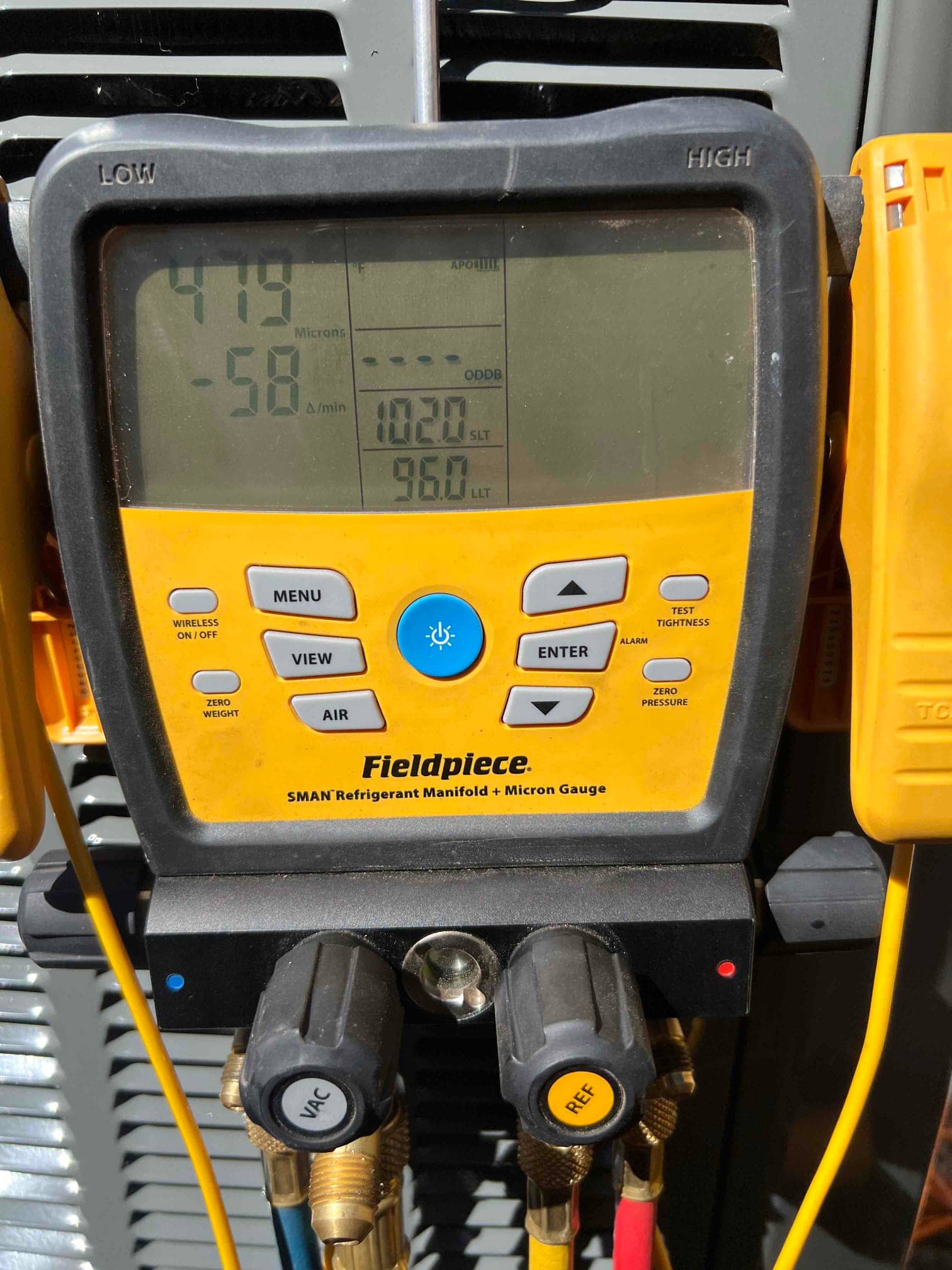 Digital micron gauge on the manifold shows 479 microns, confirming deep vacuum during system evacuation before refrigerant charging.