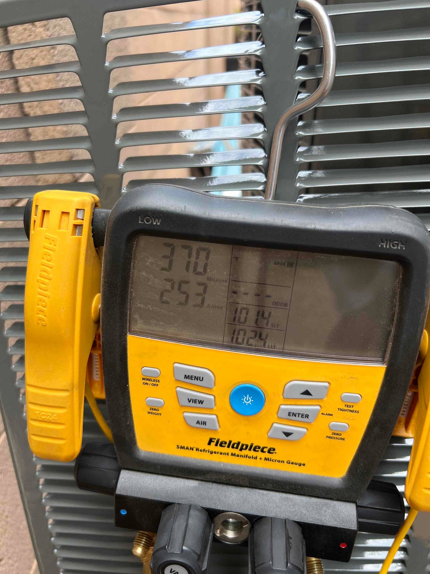 Digital micron gauge on the outdoor unit shows 370 microns, documenting a deep vacuum during system evacuation before refrigerant charging.