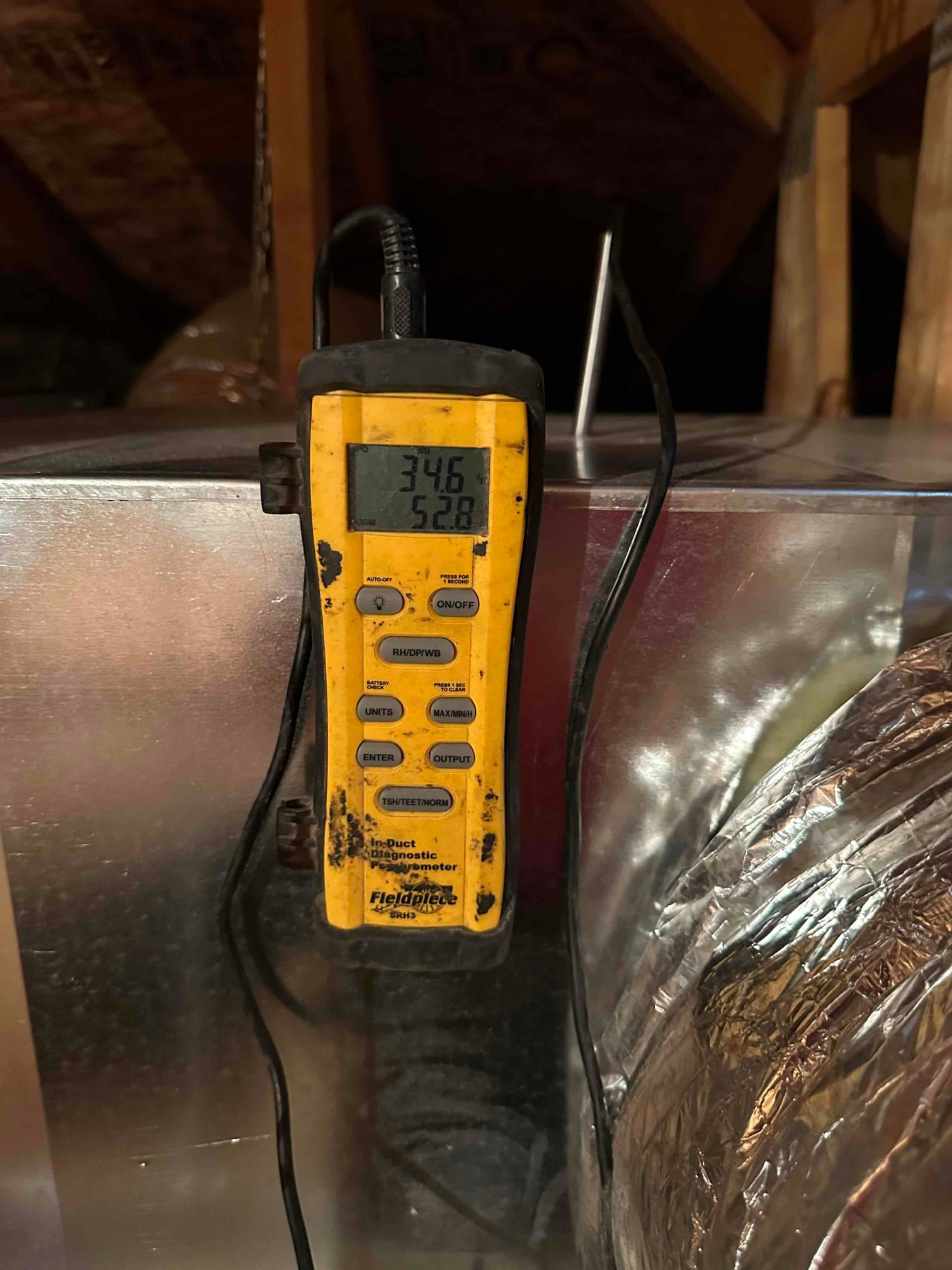 Digital probe inserted in duct shows 52.8 degrees on the display, documenting cooled supply air temperature during commissioning.