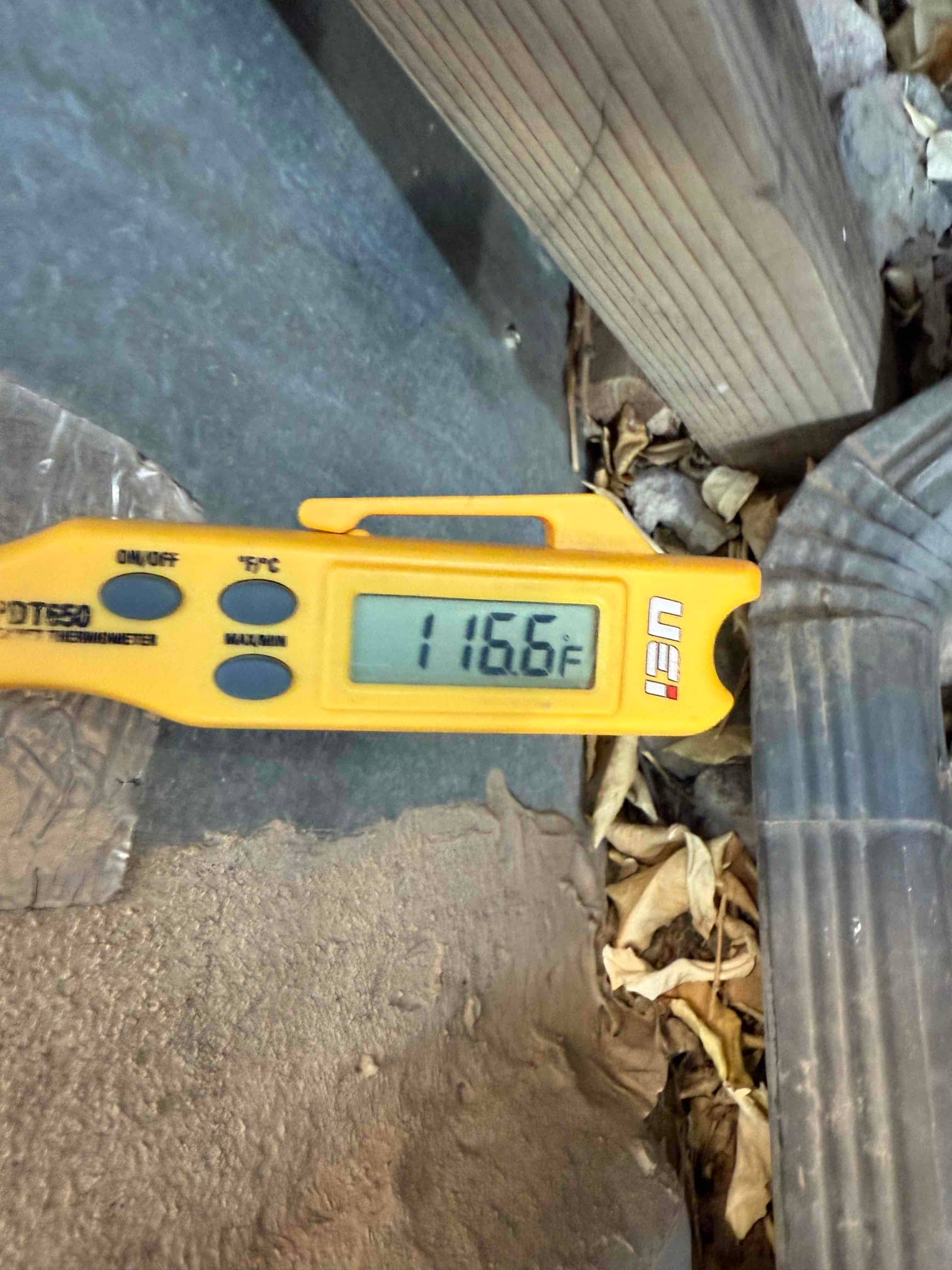 Digital thermometer displays 116.6 °F, with the probe positioned on the HVAC job site surface.