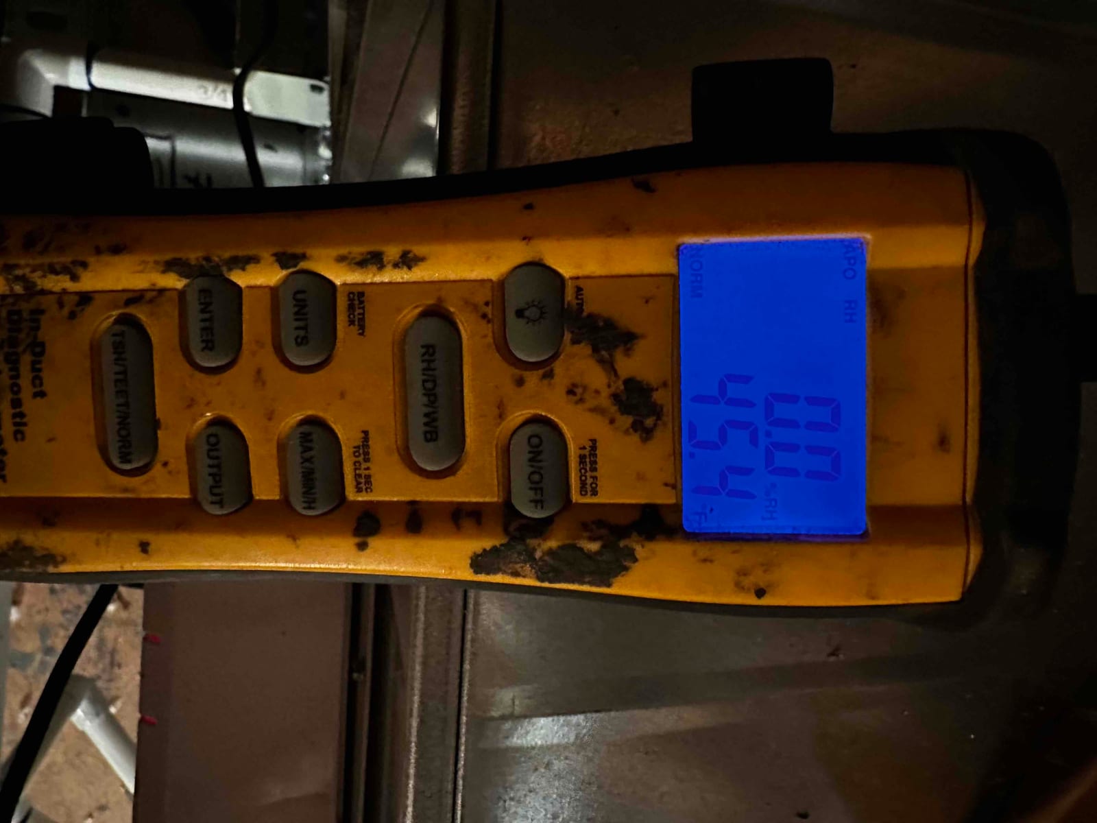 Digital thermometer displays 45.4 degrees Fahrenheit, documenting cold supply air temperature at the duct during commissioning.