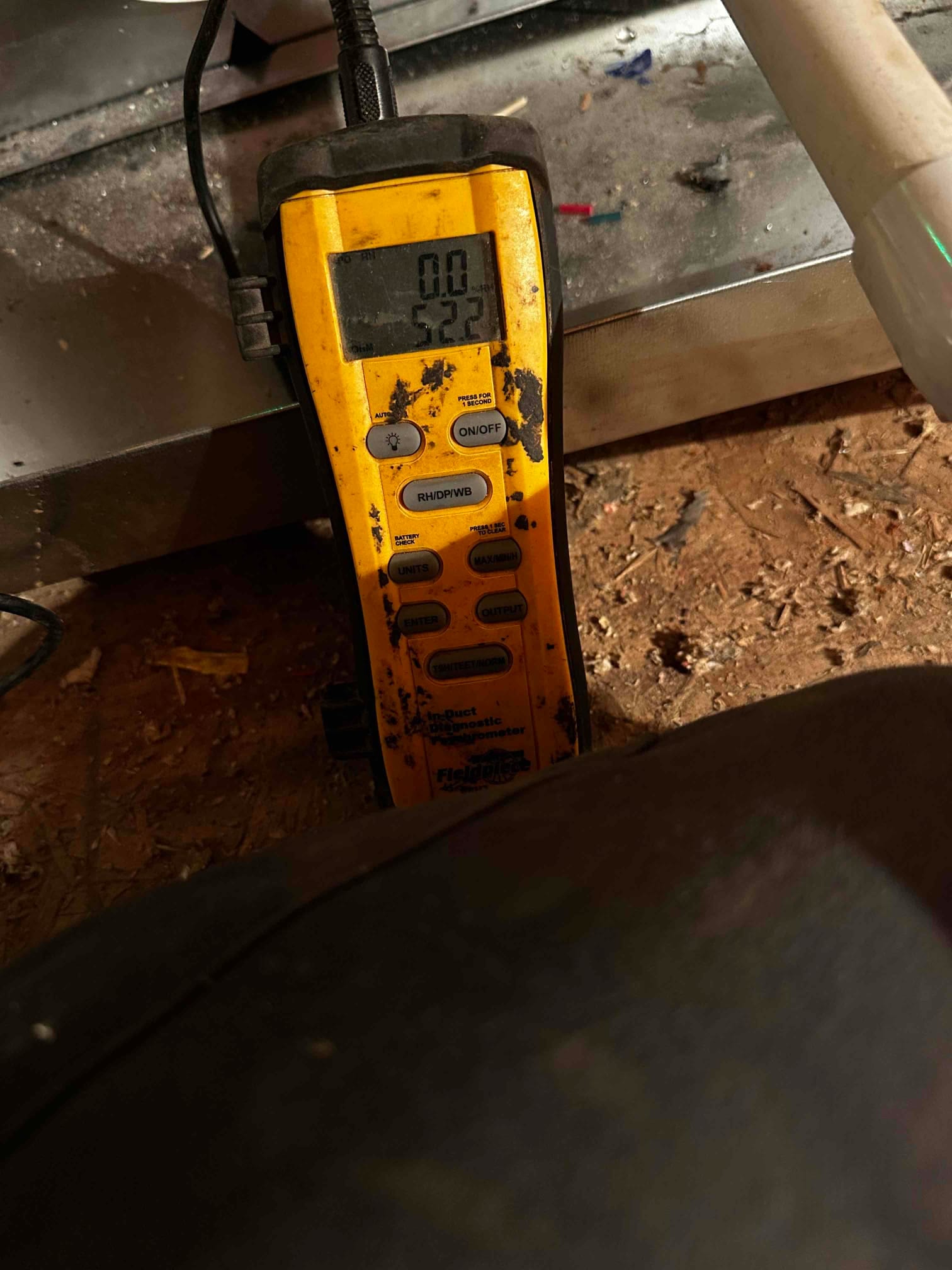 Digital thermometer displays 52.2 degrees, documenting supply air temperature during HVAC commissioning at the air handler.