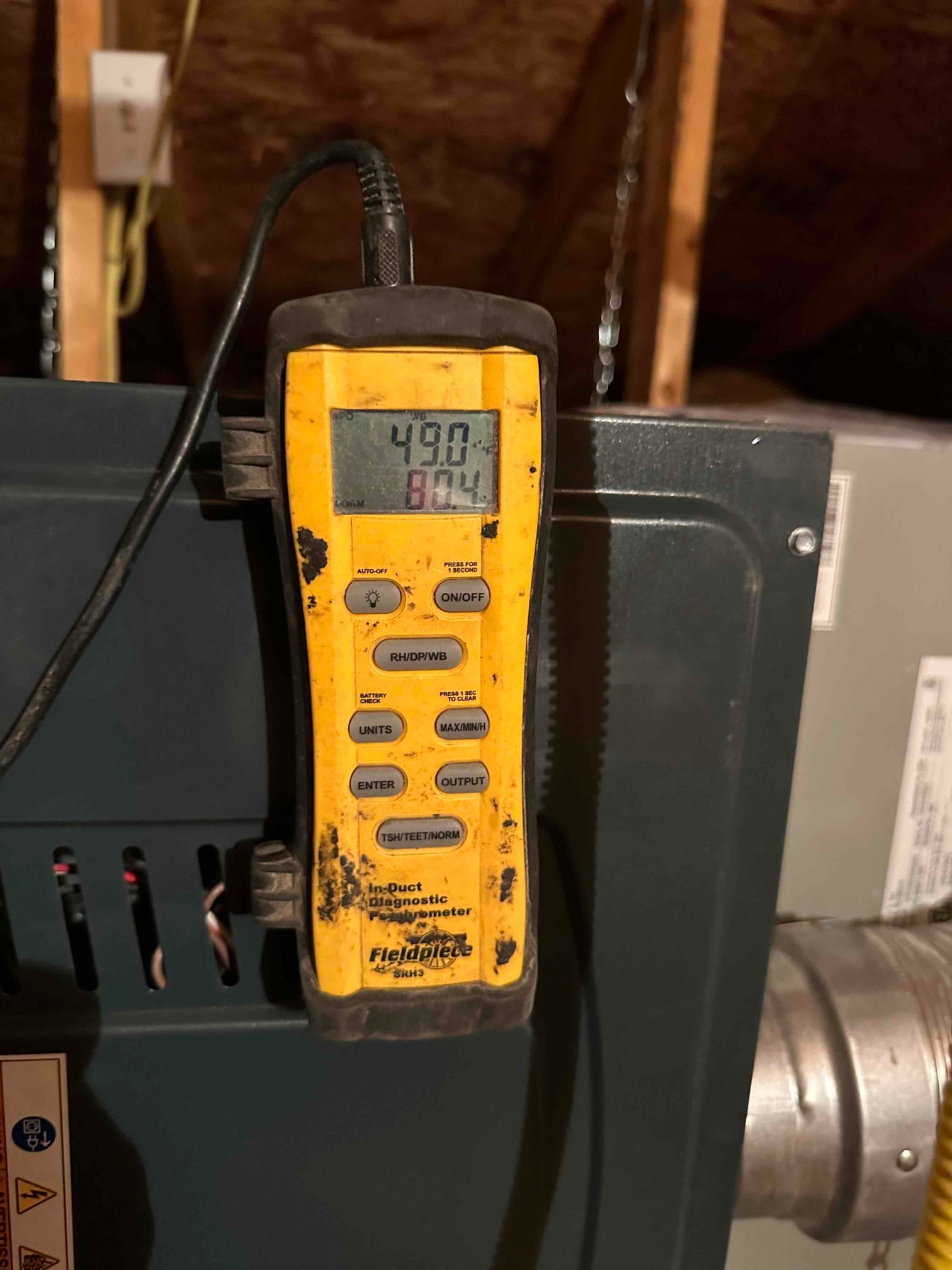 Digital thermometer on the furnace cabinet displays 49.0 degrees Fahrenheit, documenting cold supply air temperature after cooling.