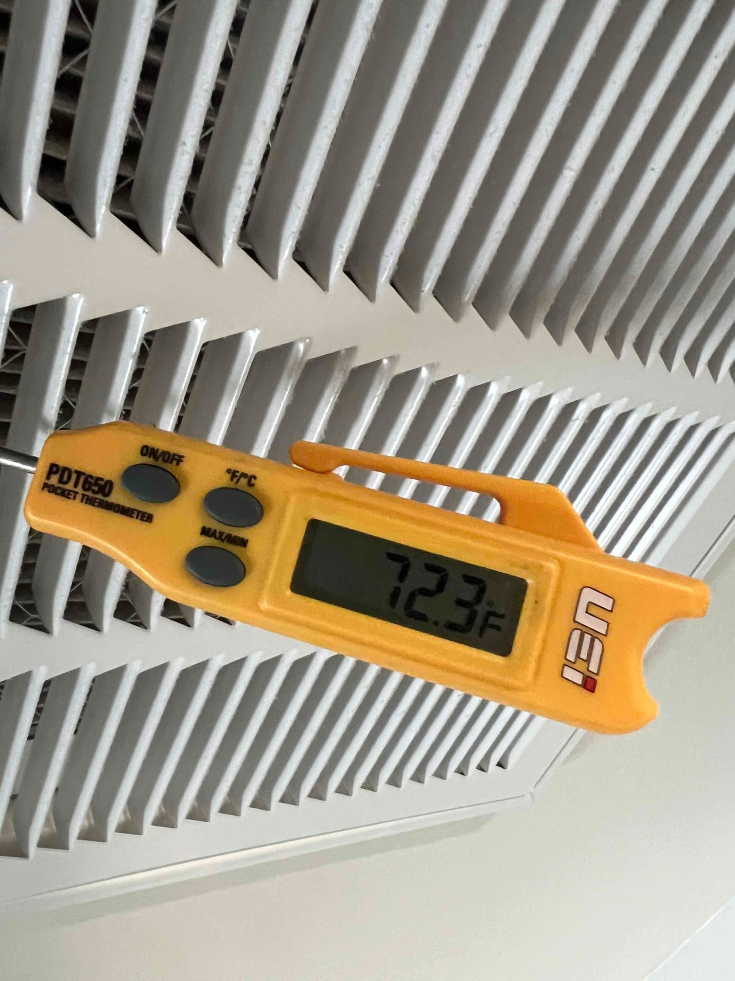 Digital thermometer inserted at a supply vent shows 72.3°F supply air temperature during air conditioning operation.