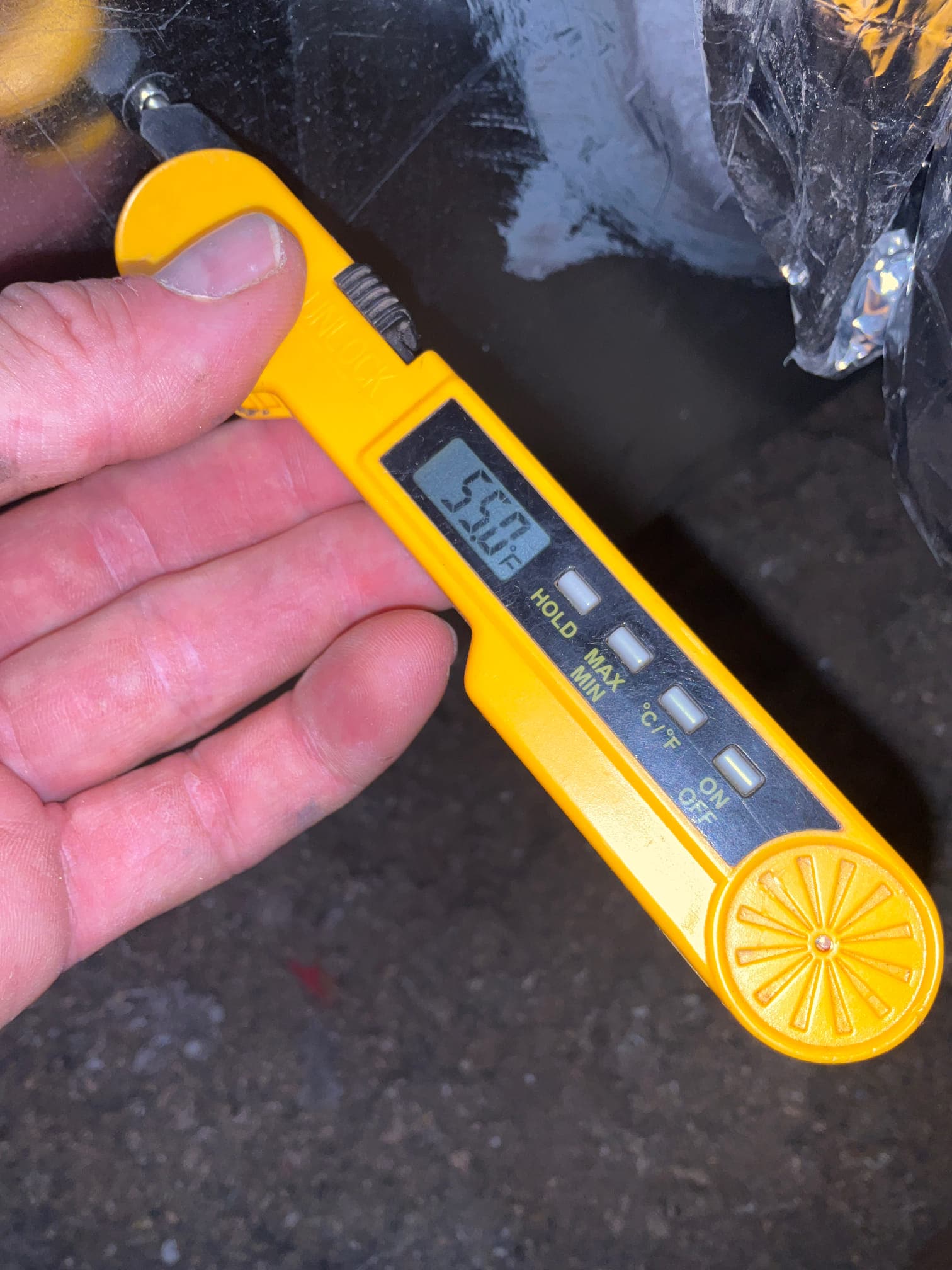 Digital thermometer probe measures 55.0°F at a duct opening, documenting supply air temperature during system commissioning.