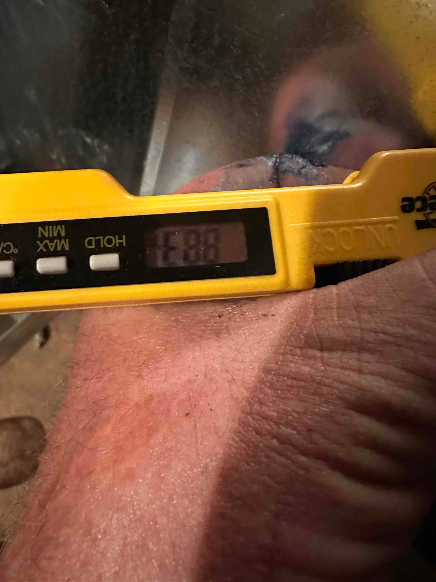 Digital thermometer probe measures air temperature at the duct, documenting airflow temperature during system commissioning.