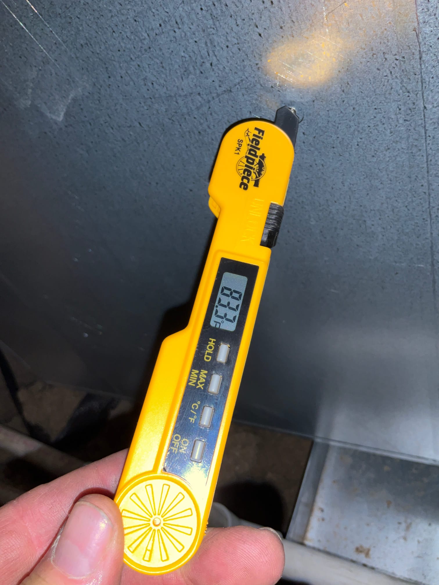 Digital thermometer shows 83.7°F while measuring air temperature at the return side of the HVAC system.