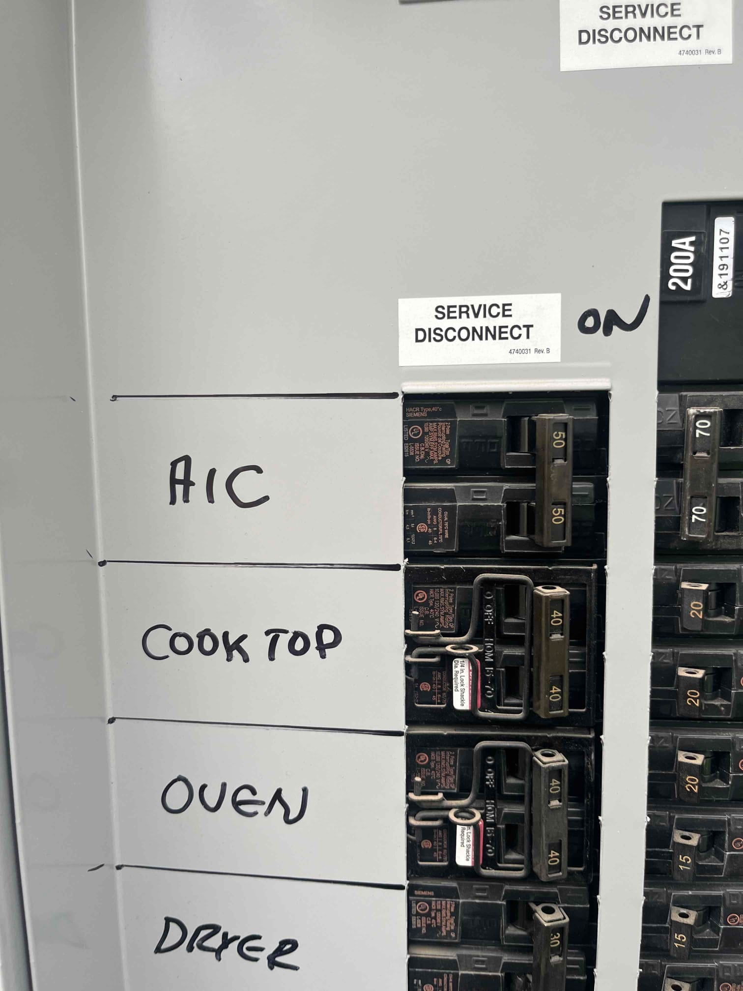 Electrical panel with labeled breakers for A/C, cooktop, oven, and dryer, showing the service disconnect in the ON position.