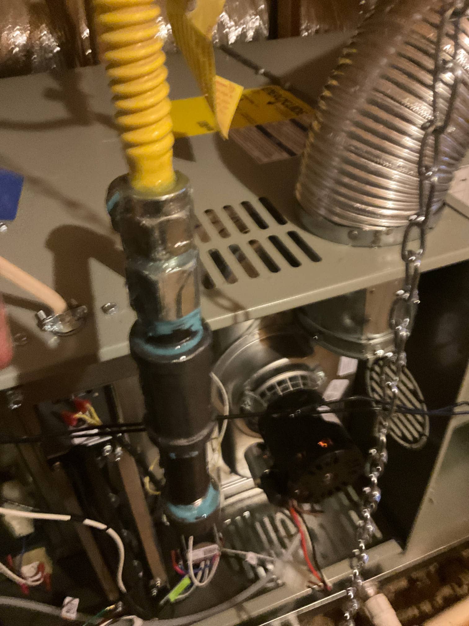Gas furnace in attic shows flex gas connector, black iron piping, induced draft motor, and connected wiring during installation.