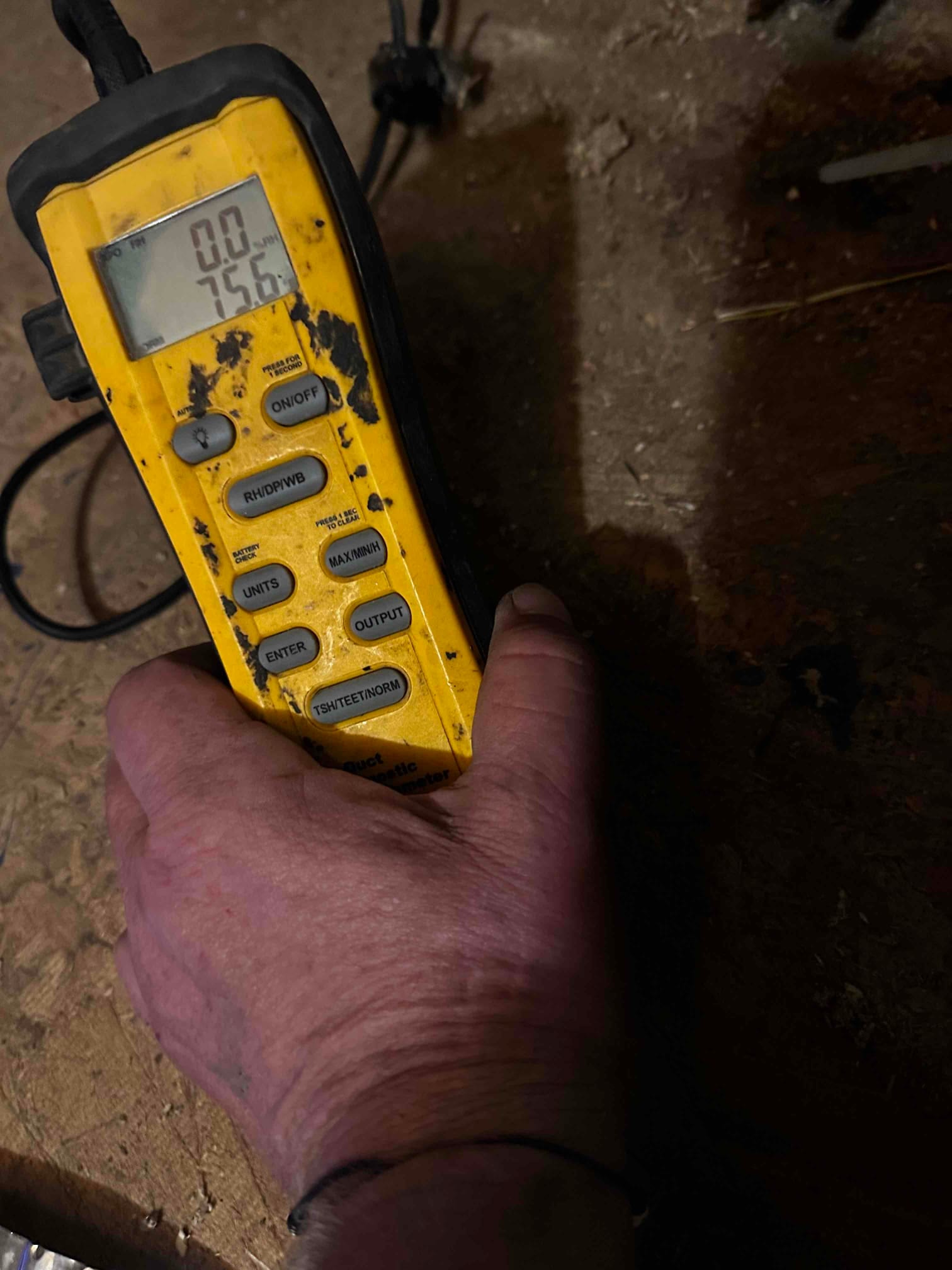 Handheld digital thermometer shows 75.6 degrees Fahrenheit during air temperature check at the HVAC installation site.