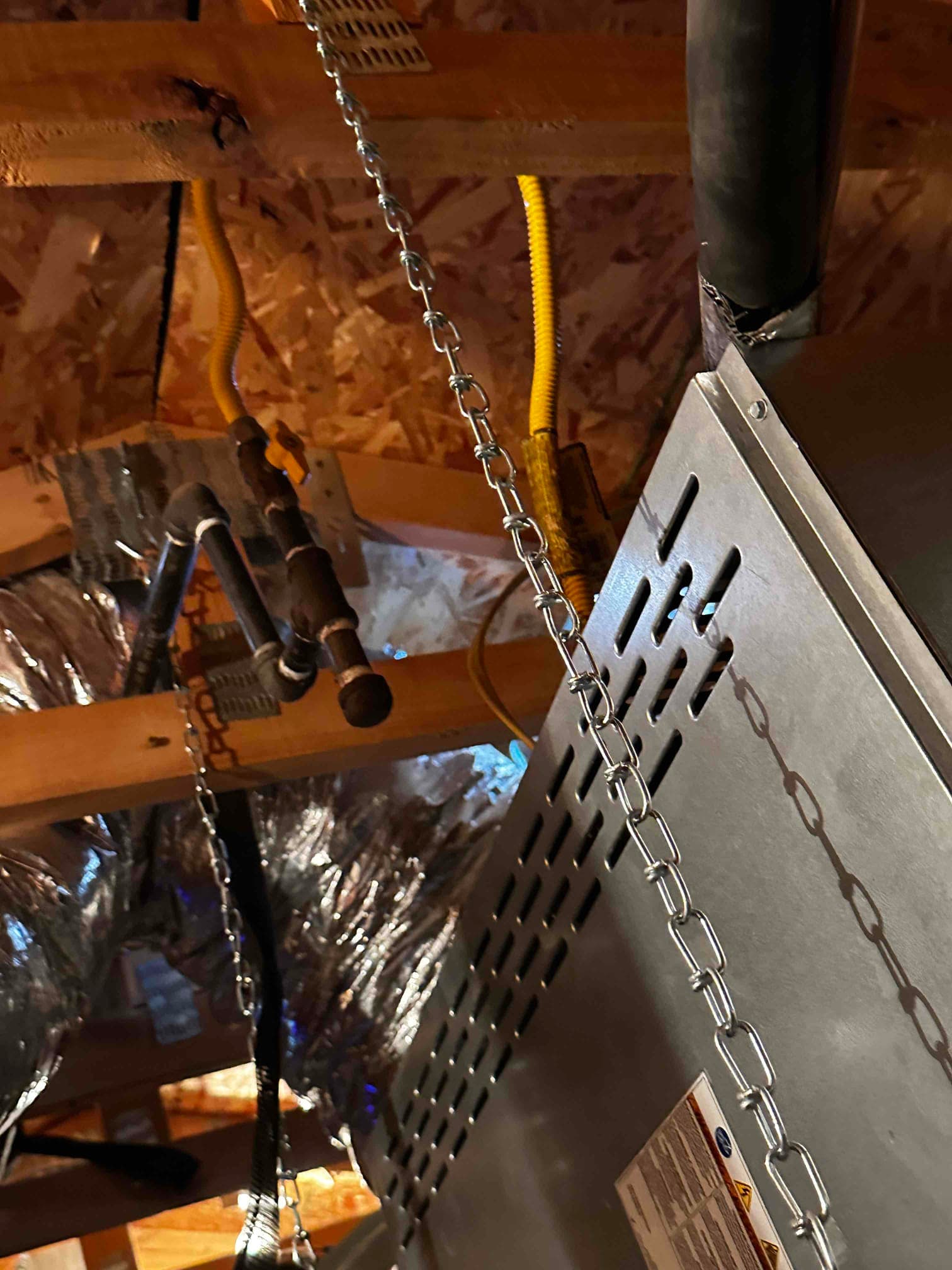 Horizontal attic air handler suspended with chains, connected to insulated ductwork and gas flex lines, showing new installation details.